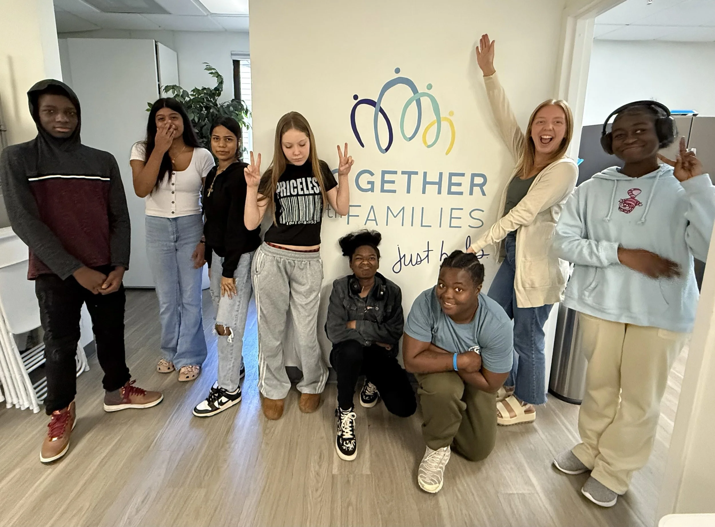 A group of teenagers posing in front of a wall with the Together with Families logo.
