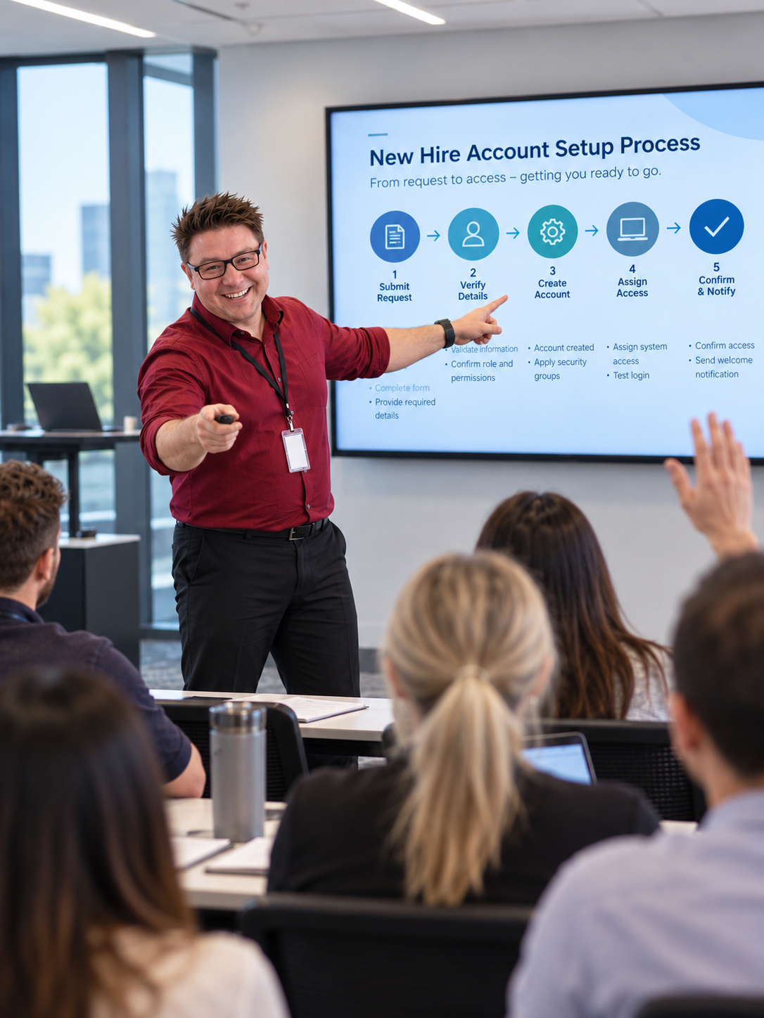 a picture of callum at the front of a classroom asking a new staff member a question while pointing to a tv screen about a new process