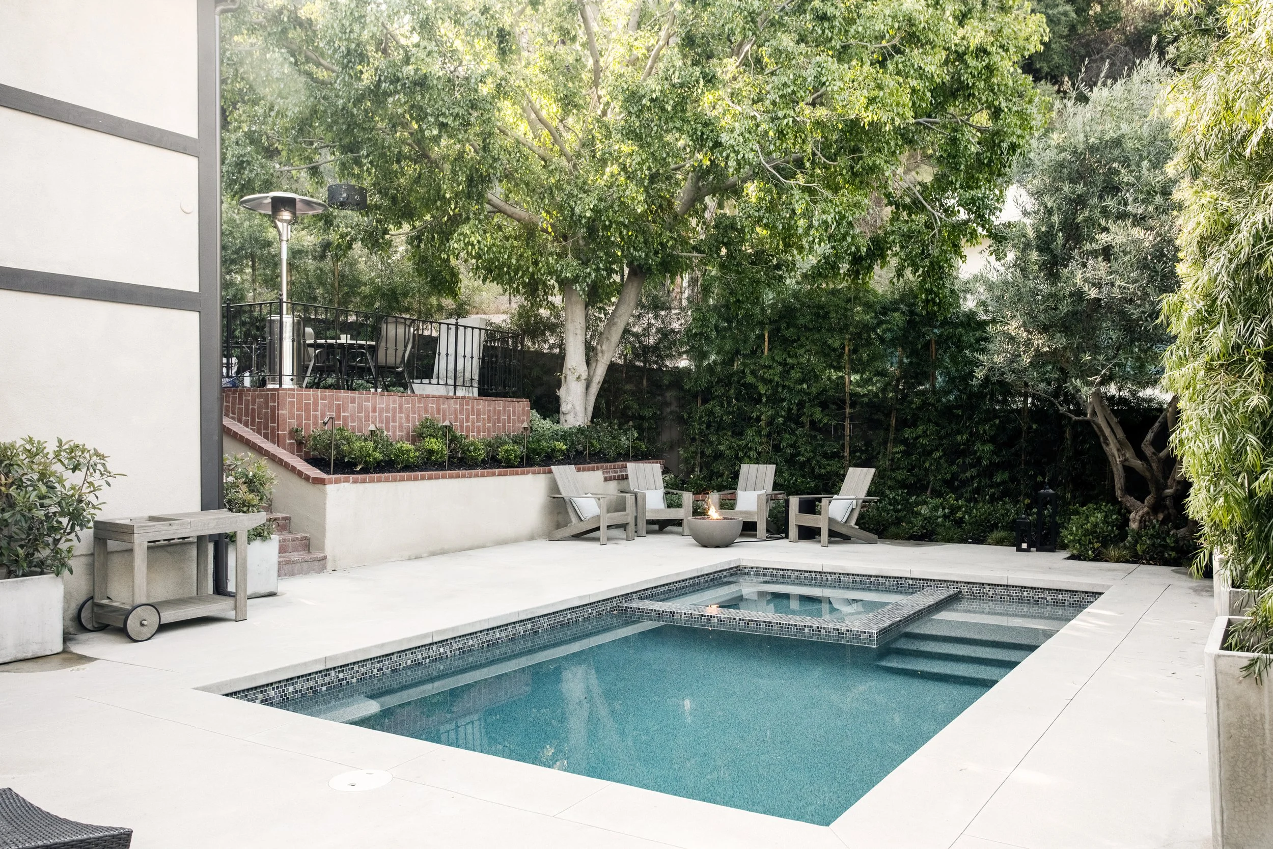 Poolside lounges, fire pit with adirondack chairs, brick courtyard with additional fire pit lounge, lush plantings with a clean natural aesthetic.