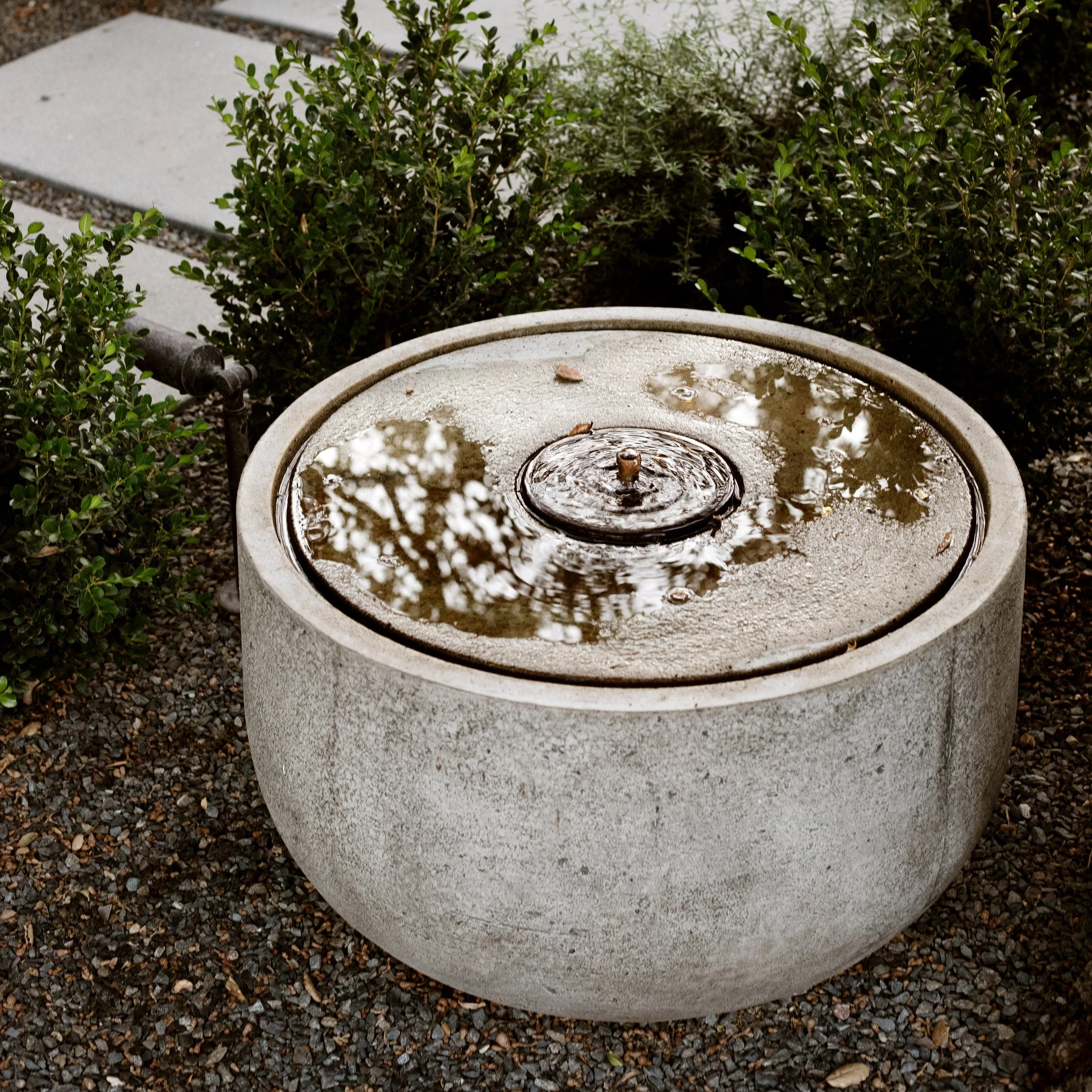 Cute bowl fountain set on gravel with plantings