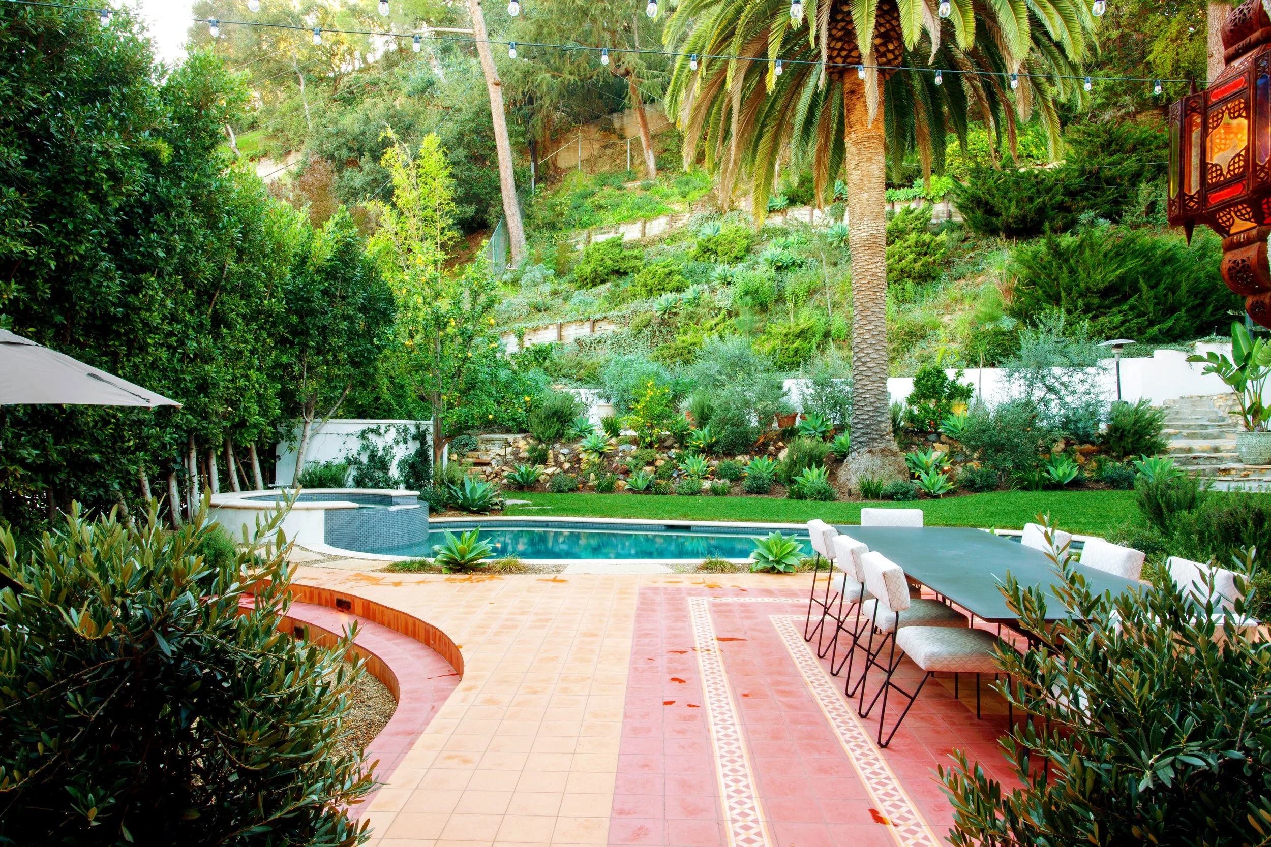 Restored Spanish estate in Hollywood Hills with new vs old terracotta tiles, layers of lush landscaping, lawn space, fire pit lounge, dining and pool.