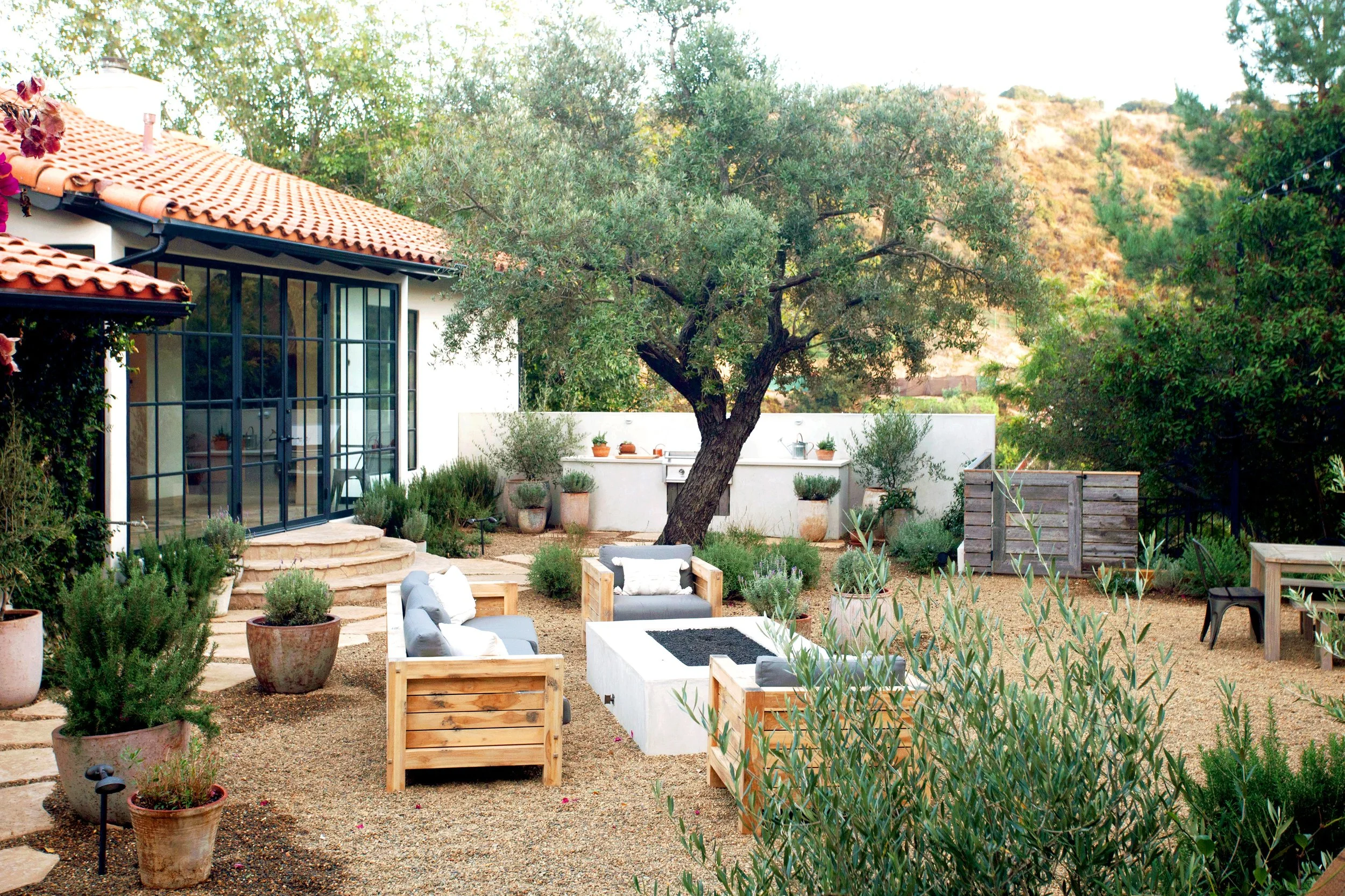 Mountain top rustic property with clean naturalistic feel, reclaimed wood fencing, Spanish elements, layered Mediterranean plantings, Mexican pebbles, and multiple lounge / dining layouts.