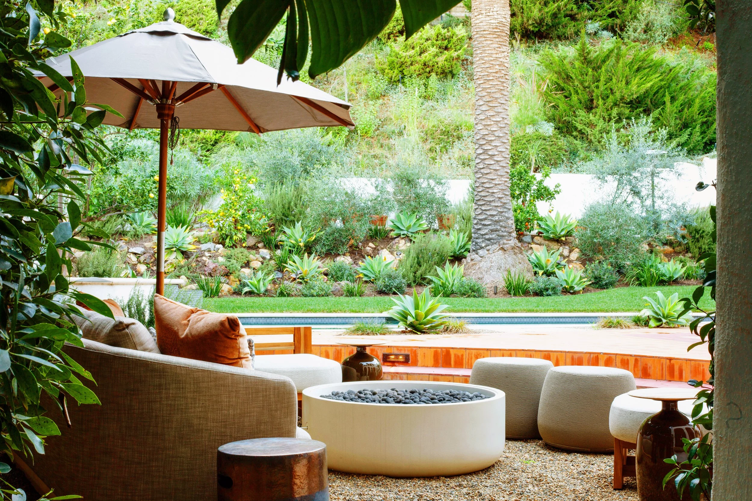 Restored Spanish estate in Hollywood Hills with new vs old terracotta tiles, layers of lush landscaping, lawn space, fire pit lounge, dining and pool.