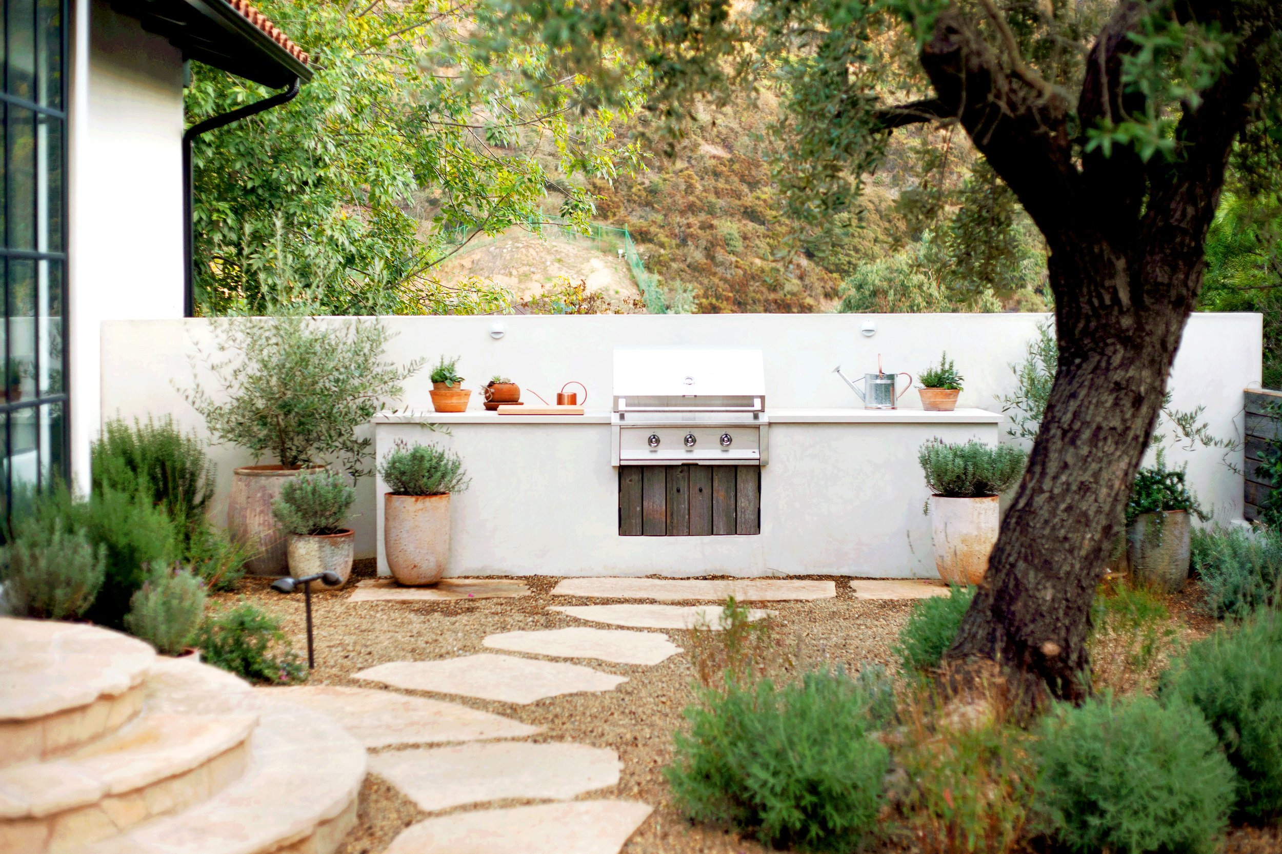 Large rustic BBQ island with two parallel counters, stools and Argentine grill