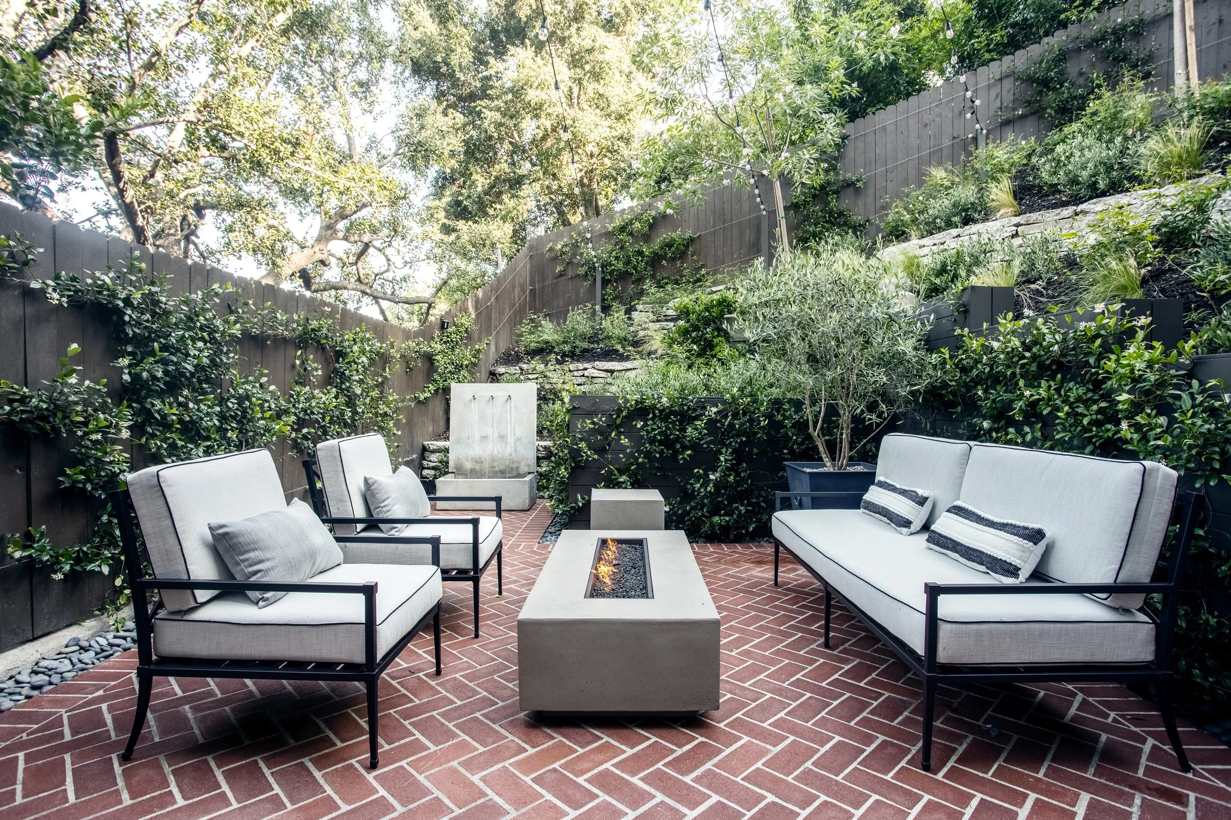Poolside lounges, fire pit with adirondack chairs, brick courtyard with additional fire pit lounge, lush plantings with a clean natural aesthetic.