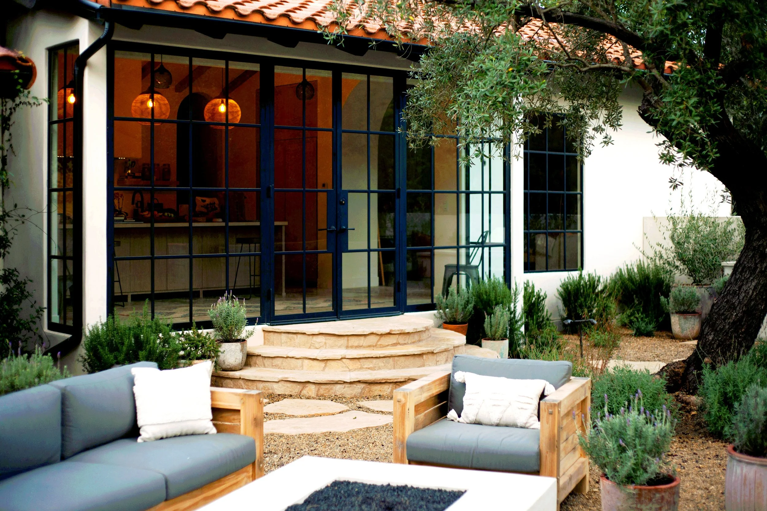 Mountain top rustic property with clean naturalistic feel, reclaimed wood fencing, Spanish elements, layered Mediterranean plantings, Mexican pebbles, and multiple lounge / dining layouts.