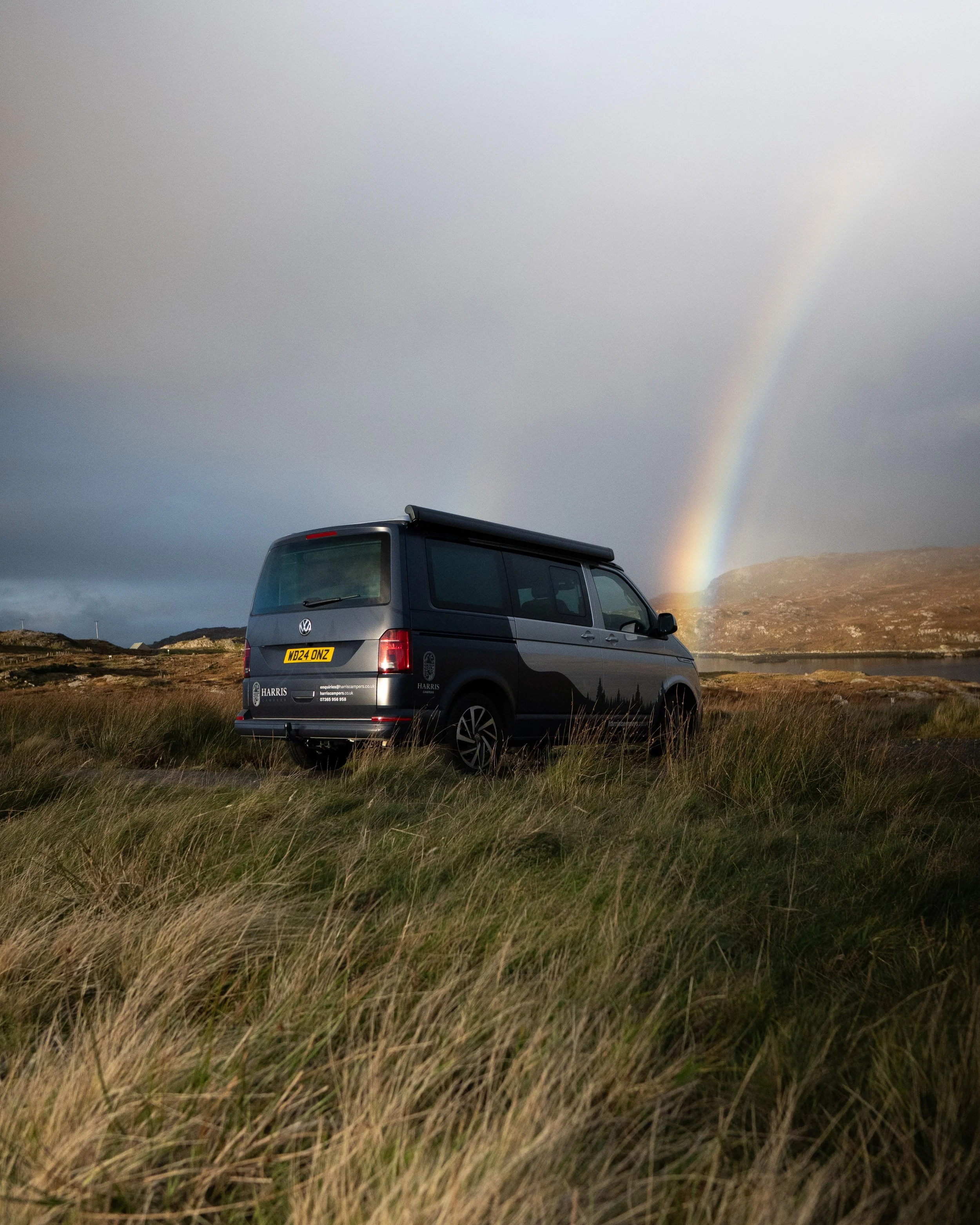 Campervan hire Scotland, Campervan hire Glasgow, Harris Campers camper van parked on the Scottish Highlands with a rainbow in the background.