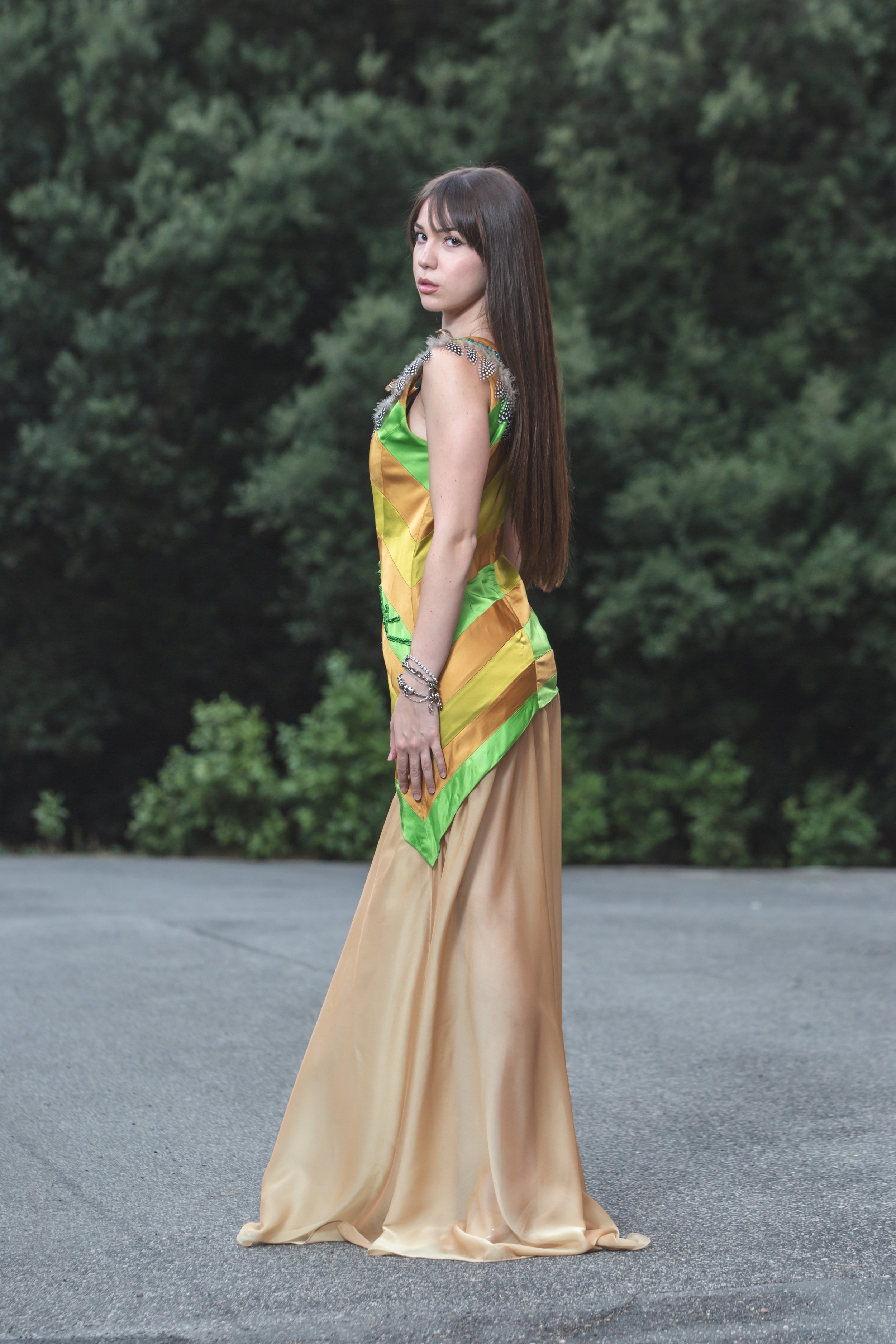 abito realizzato con strisce realizzate a mano in diversi colori di duchesse cuciti insieme che vanno dal sabbia, verde acido e verde erba. Lo scolloè molto particolare, decorato e ricamato a mano con perline dorate e bronzo, passamanerie verdi e piu