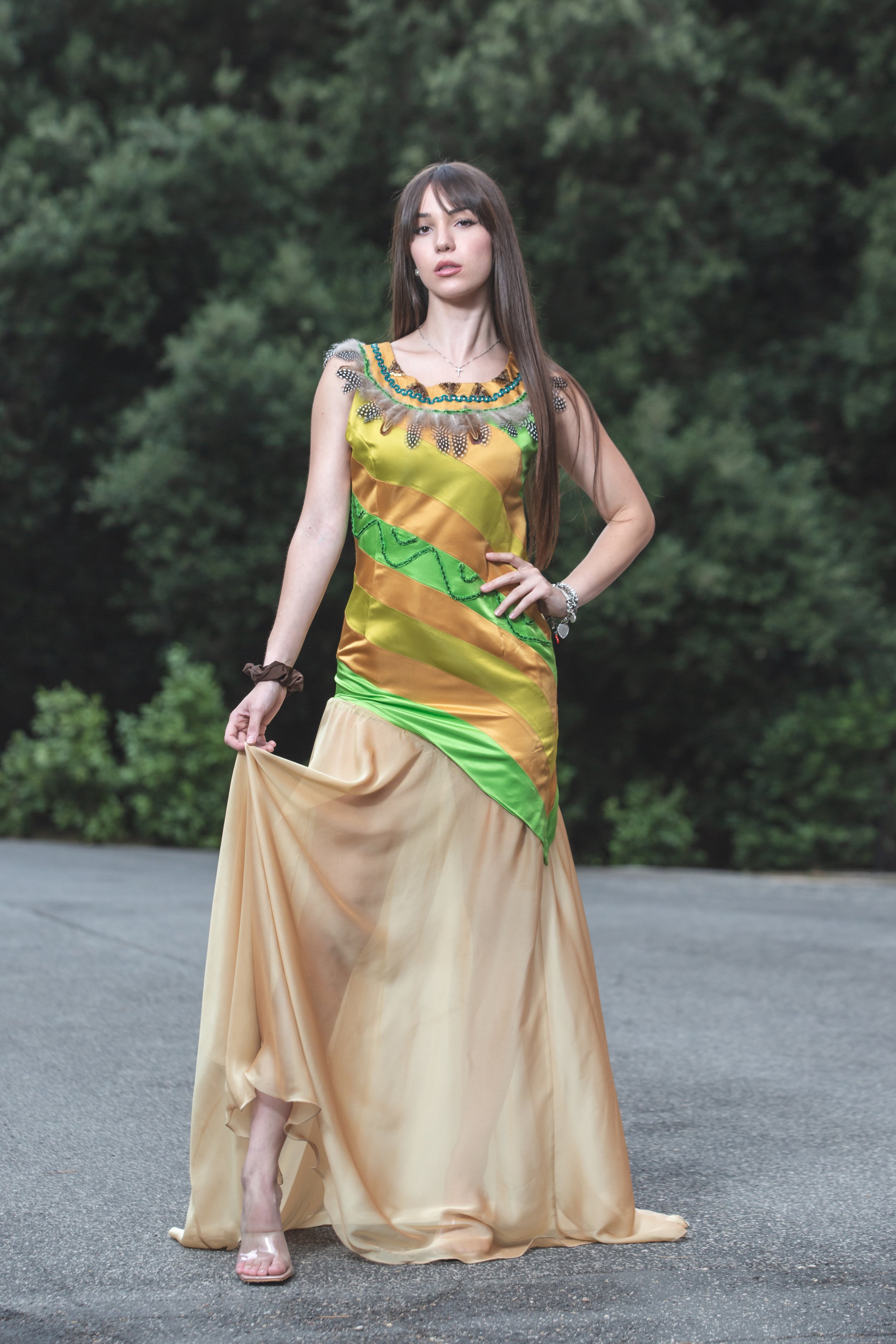 abito realizzato con strisce realizzate a mano in diversi colori di duchesse cuciti insieme che vanno dal sabbia, verde acido e verde erba. Lo scolloè molto particolare, decorato e ricamato a mano con perline dorate e bronzo, passamanerie verdi e piu