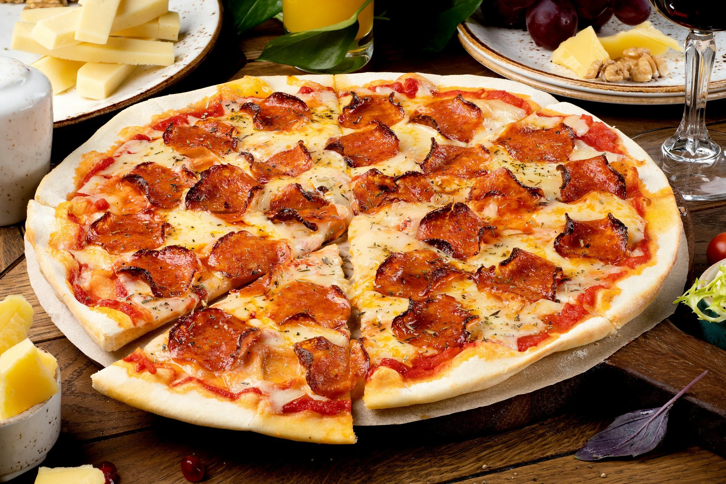 Pepperoni pizza surrounded by other snacks and drinks