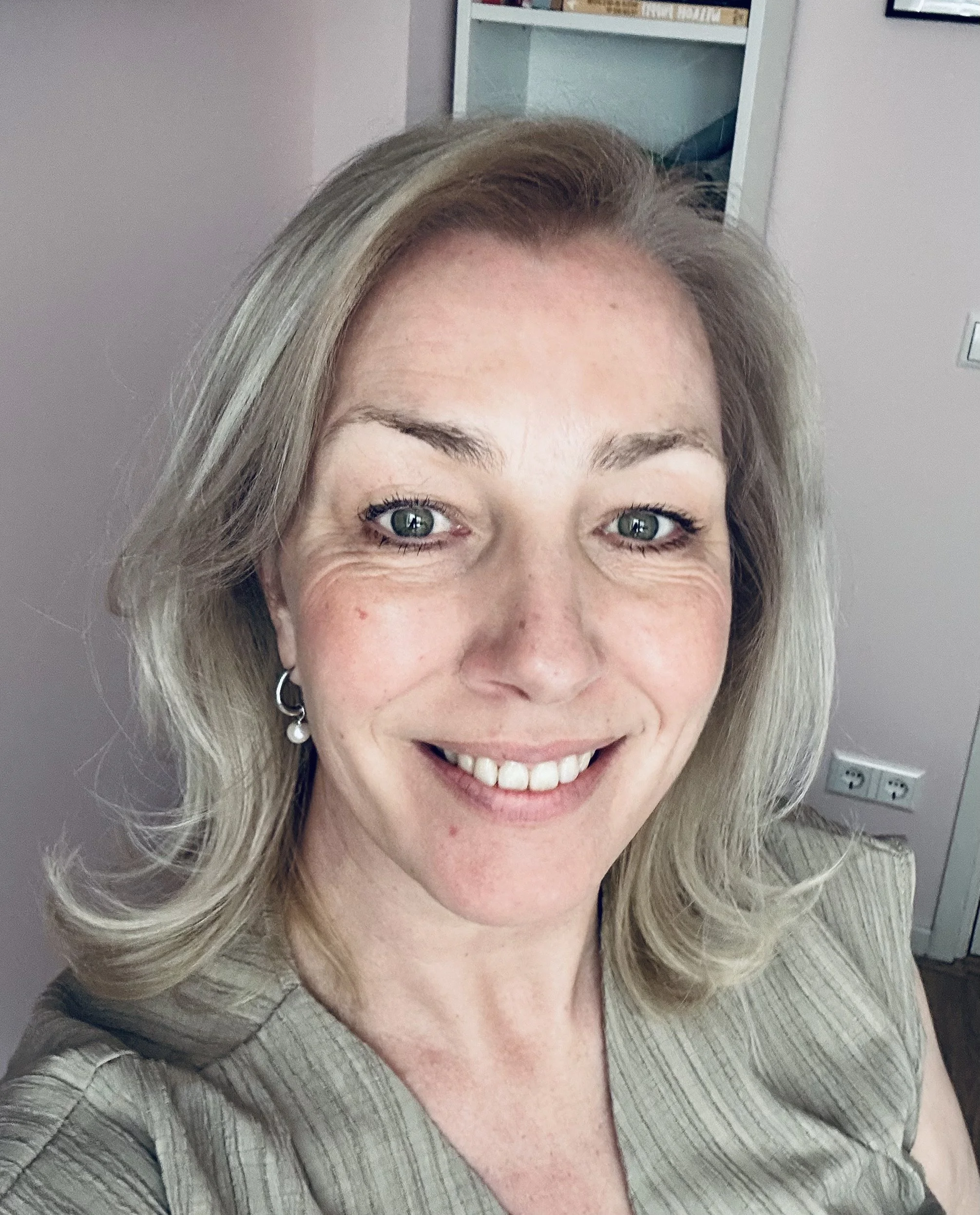 Lachende vrouw met blond haar met grijze achtergrond.