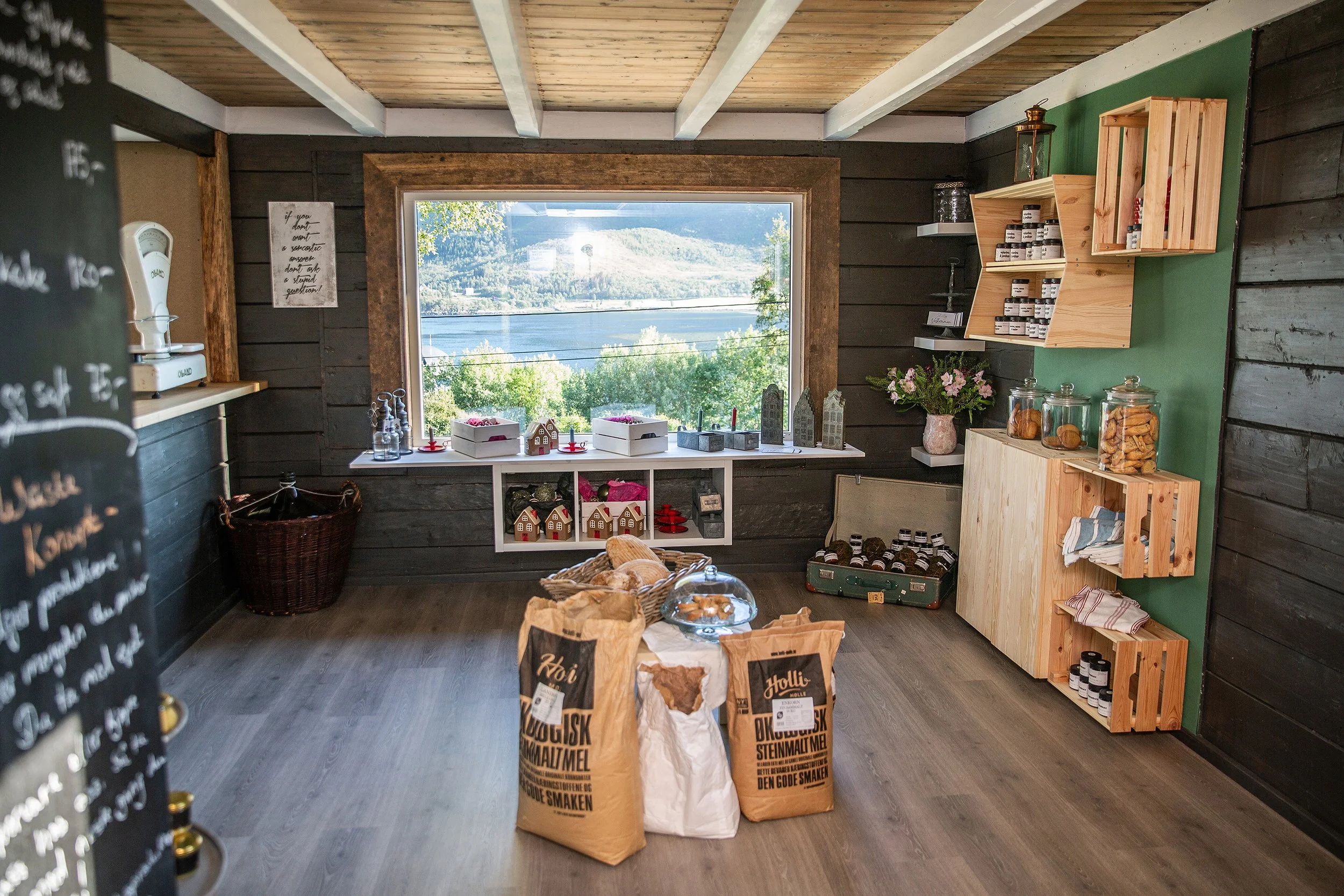 Butikken på Refsnes med hyller og varer, og et stort vindu med utsikt over fjorden.