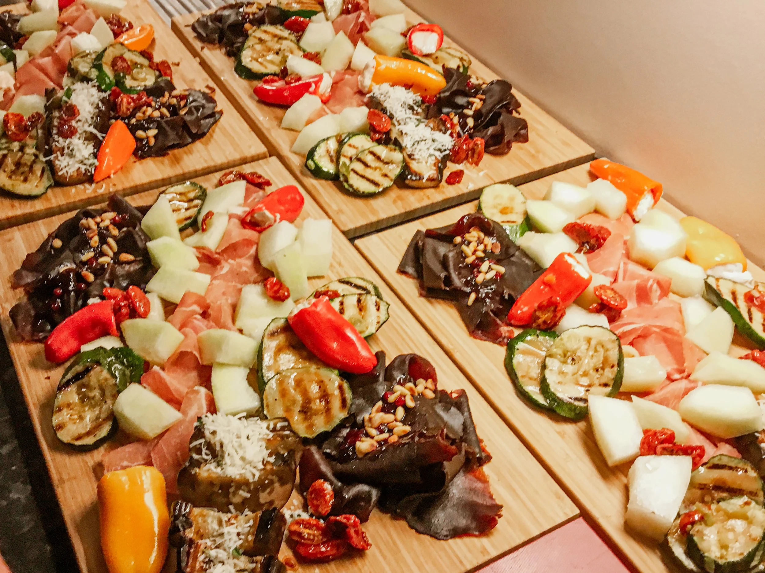 Tapasretter på trebrett. Grillet squash, fylt paprika, melon, skinke, soltørket tomat, pinjekjerner med mer.