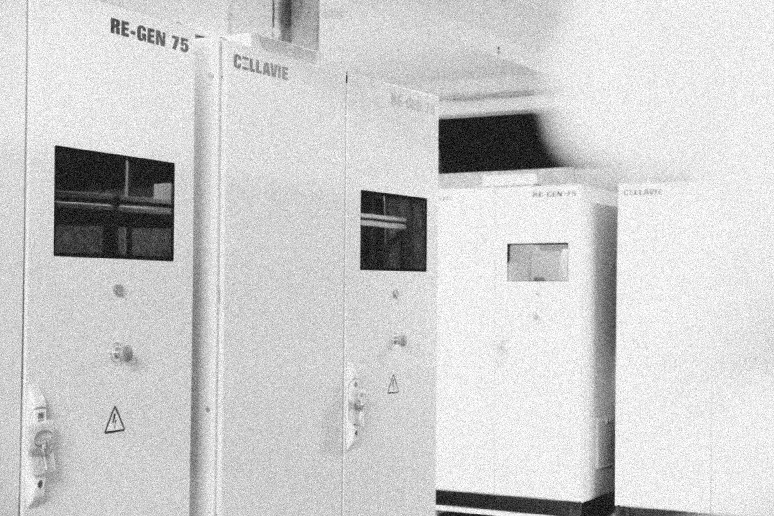 Black and white photo of electrical equipment or electrical panel with labels that include 'RE-GEN 75' and 'CELL/IE', and warning symbols.