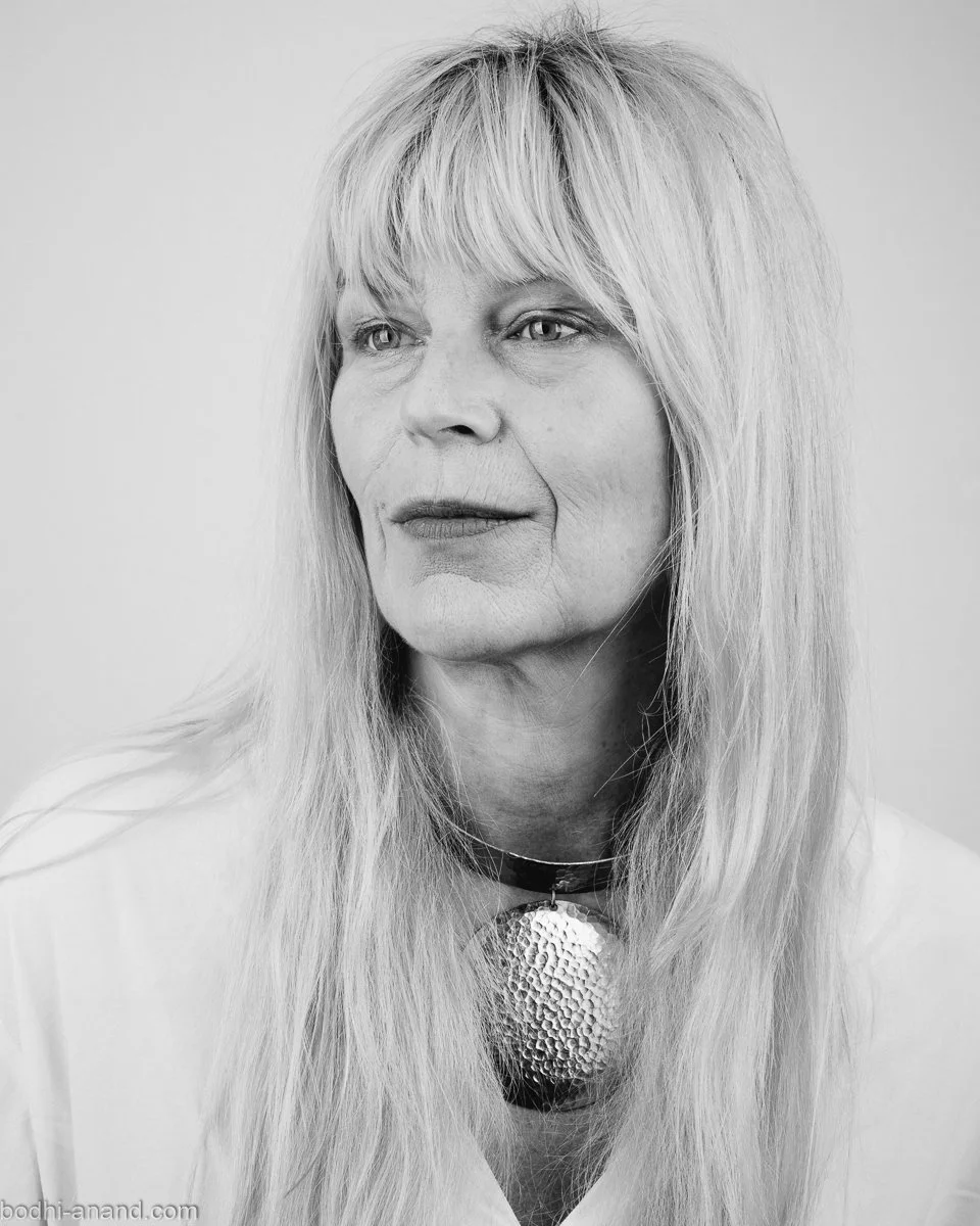 Black-and-white portrait of a woman with long hair and a pendant necklace.