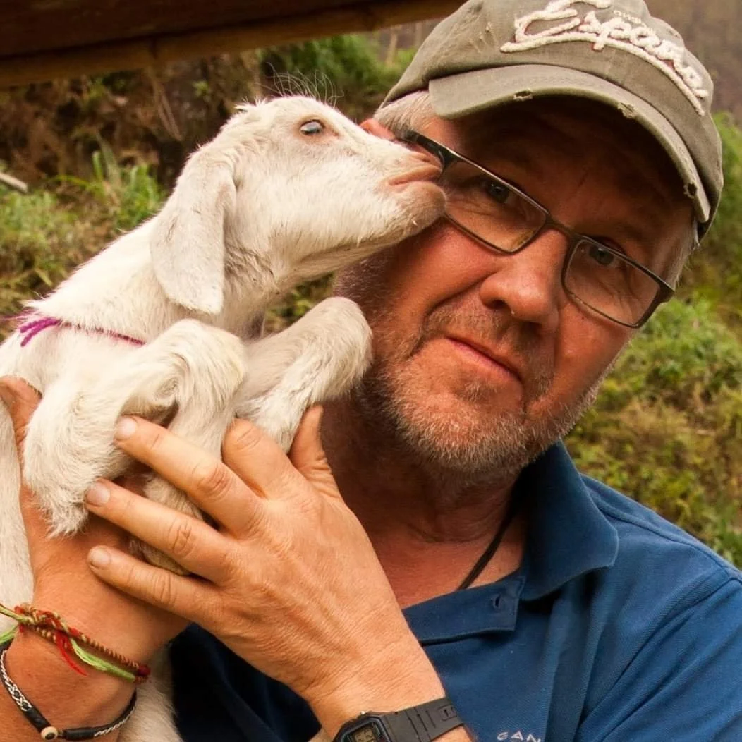 Photographer Peter Ullberg holding a young goat outdoors.