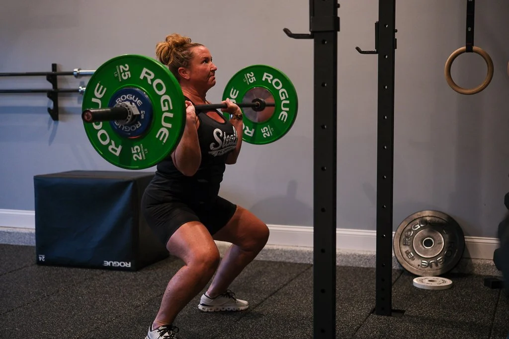 Woman lifting a barbell with green weight plates in a saint augustine, fl gym