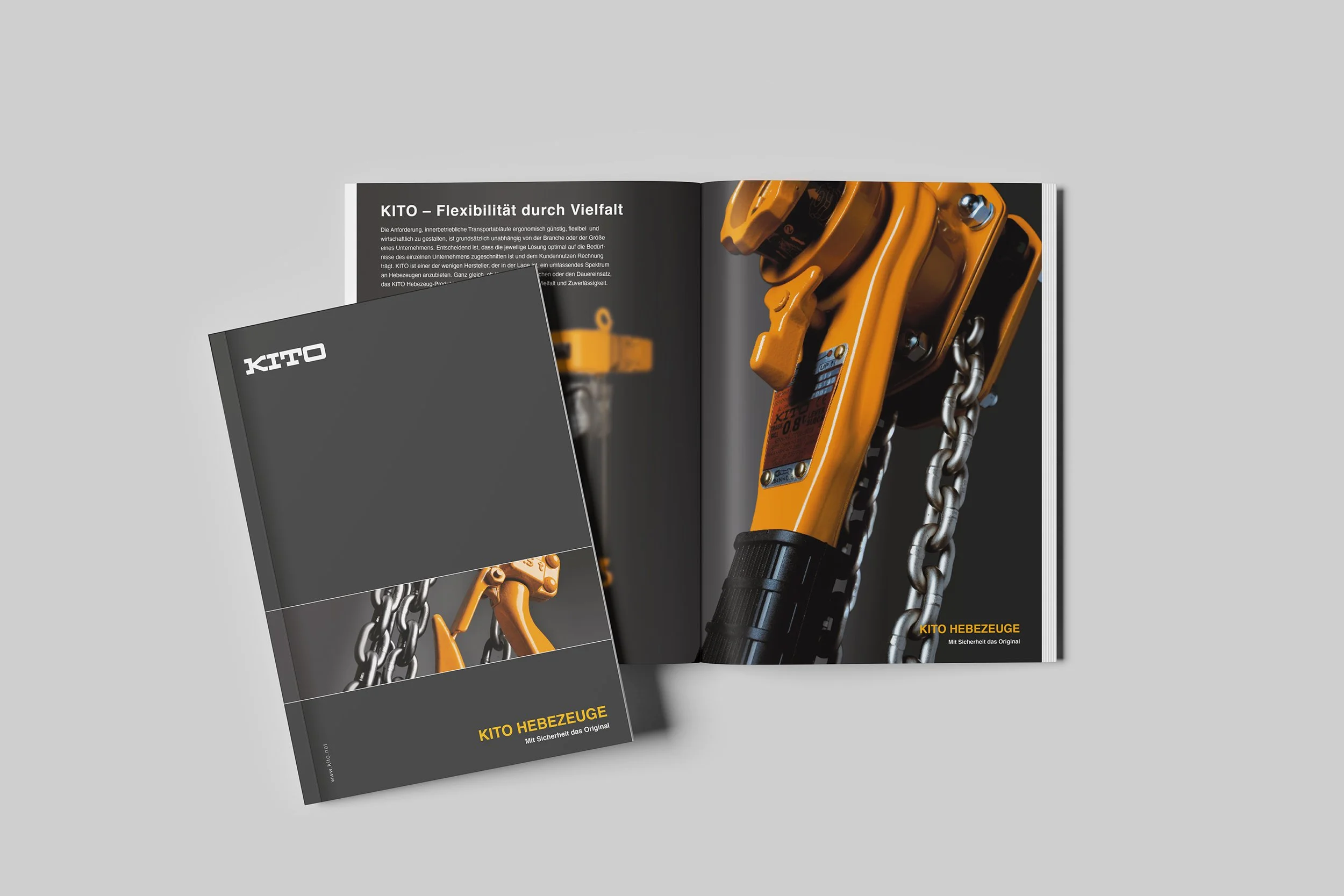 Zwei Kataloge mit dem Titel 'KITO Hebezeuge' liegen auf einem hellgrauen Hintergrund. Der eine Katalog zeigt das Titelbild mit einem Kettenzug in Nahaufnahme, der in Orange und Metalltönen gehalten ist. Der offene Katalog daneben zeigt auf einer Seit