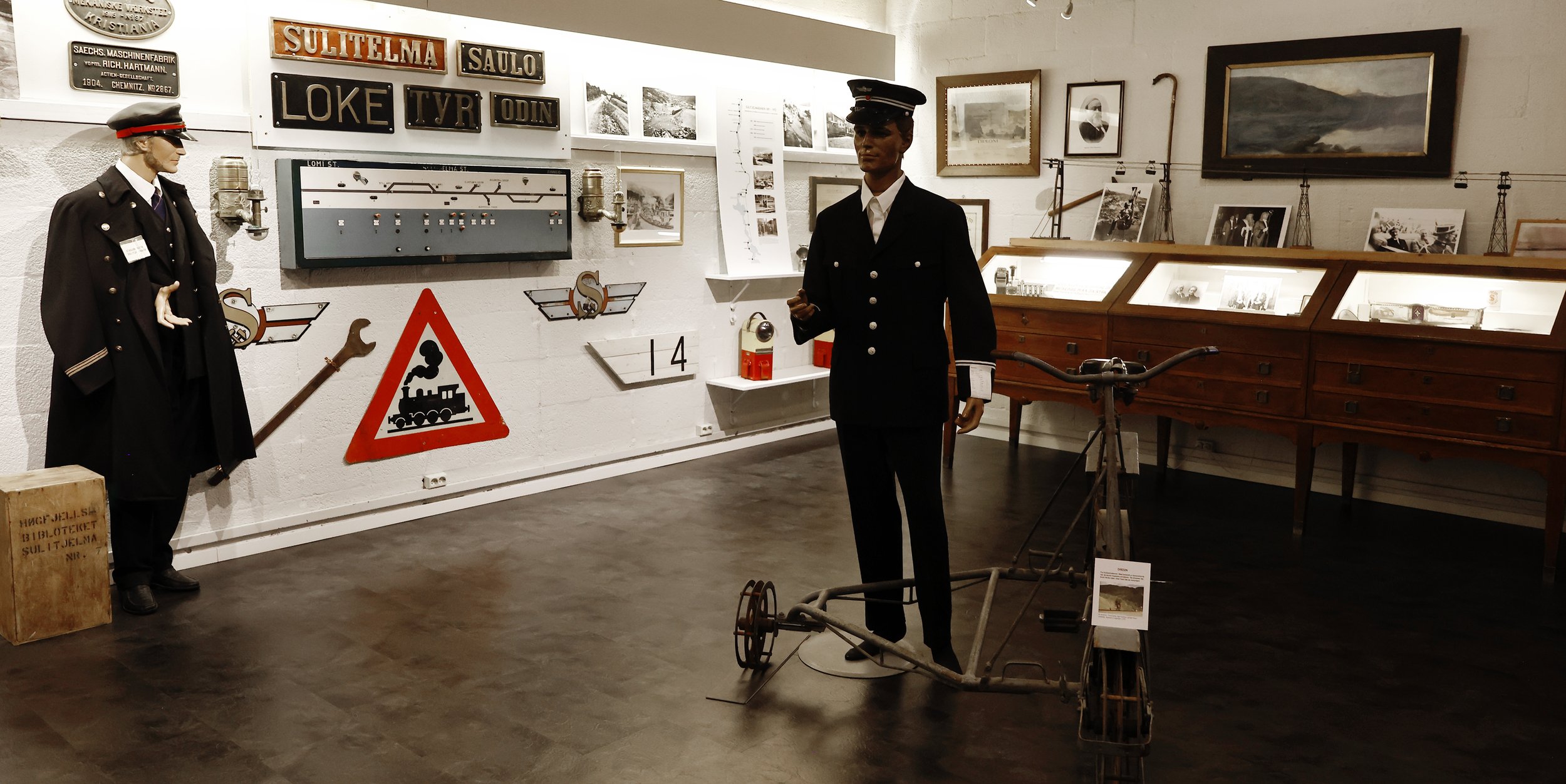 Exhibition of railway-related objects and historical photographs, including models, old signs and clothing of railway personnel, in a museum.
