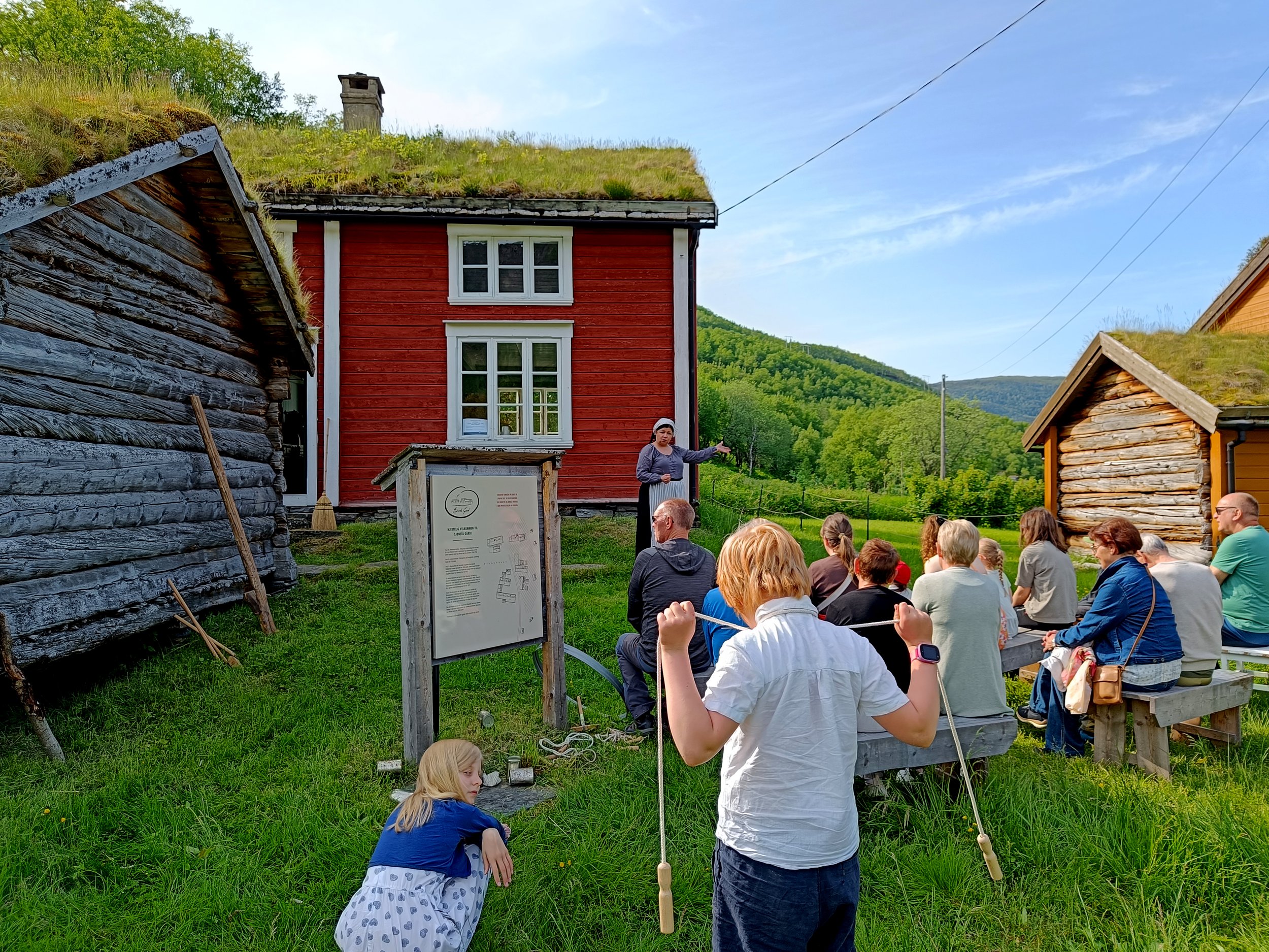 Hytter langs en innsjø omgitt av grønne trær og fjell