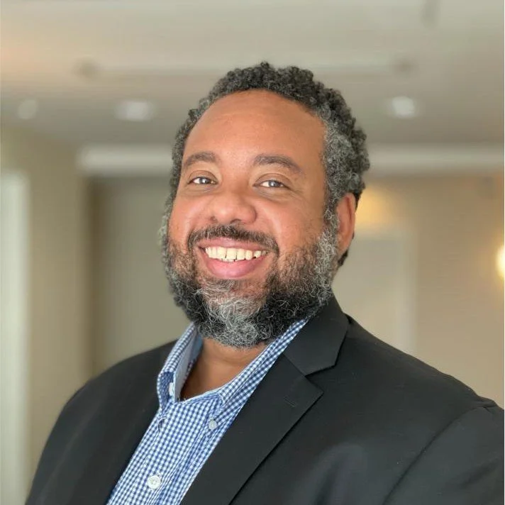 Smiling man in a suit jacket and checkered shirt