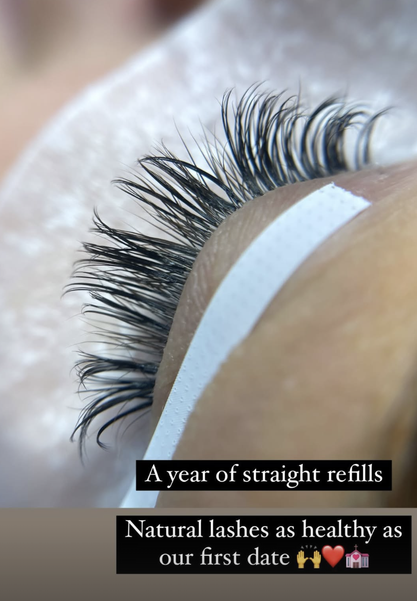 Close-up of a person's eye with long, natural eyelashes, with text overlay saying, 'A year of straight refills. Natural lashes as healthy as our first date' with various emojis.