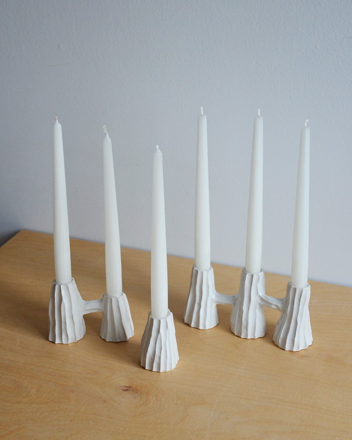 Collection of white ceramic candleholders with grooved texture, available as single, double, and triple designs—perfect for adding minimalist elegance to everyday settings or as a unique gift.
