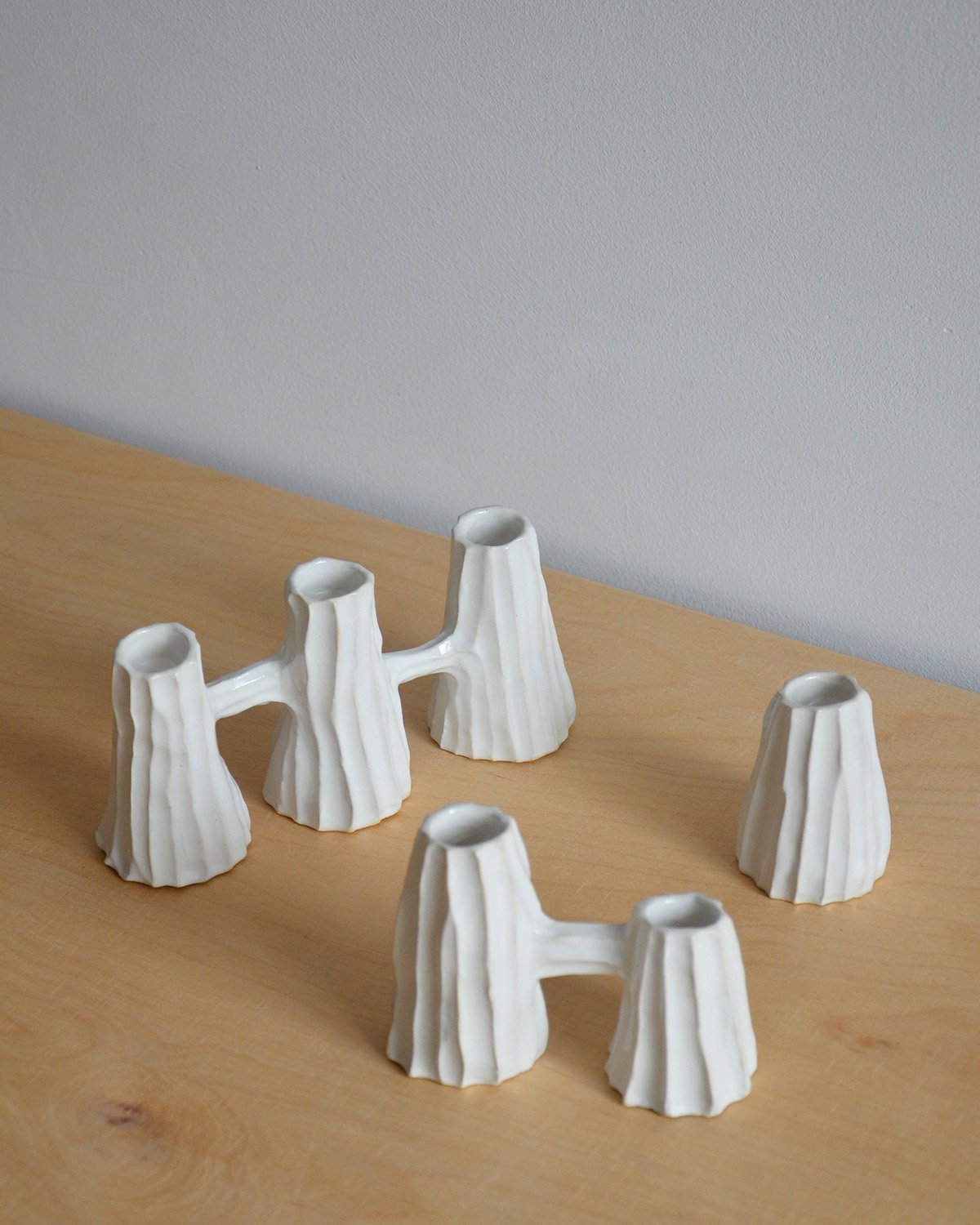 Collection of white ceramic candleholders with grooved texture, available as single, double, and triple designs—perfect for adding minimalist elegance to everyday settings or as a unique gift.