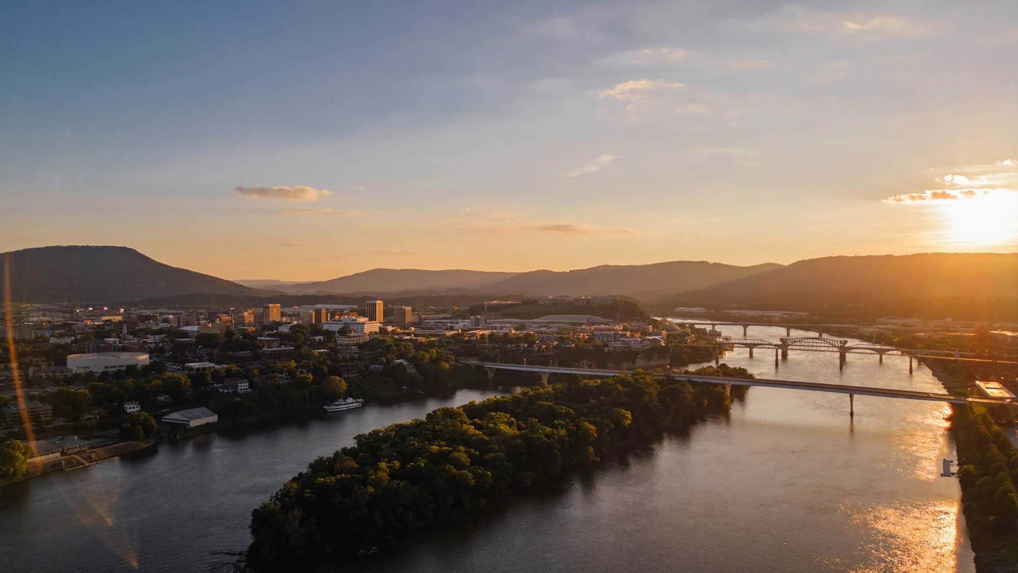 Aerial view of downtown Chattanooga, Tennessee at sunset with the Tennessee River, bridges, and surrounding mountains visible