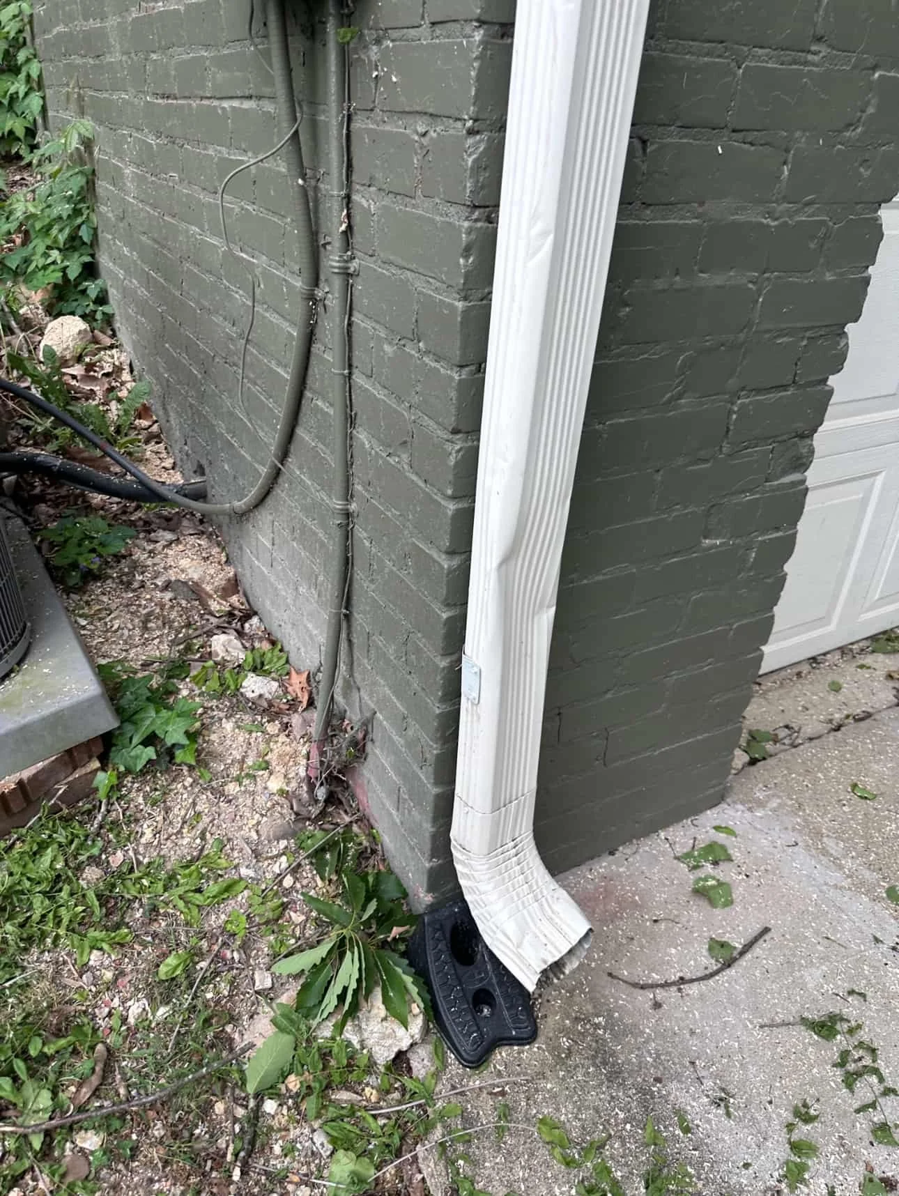 Close-up of a dented gutter downspout at the base of a home, showing damage that can affect proper water drainage in Chattanooga, Tennessee
