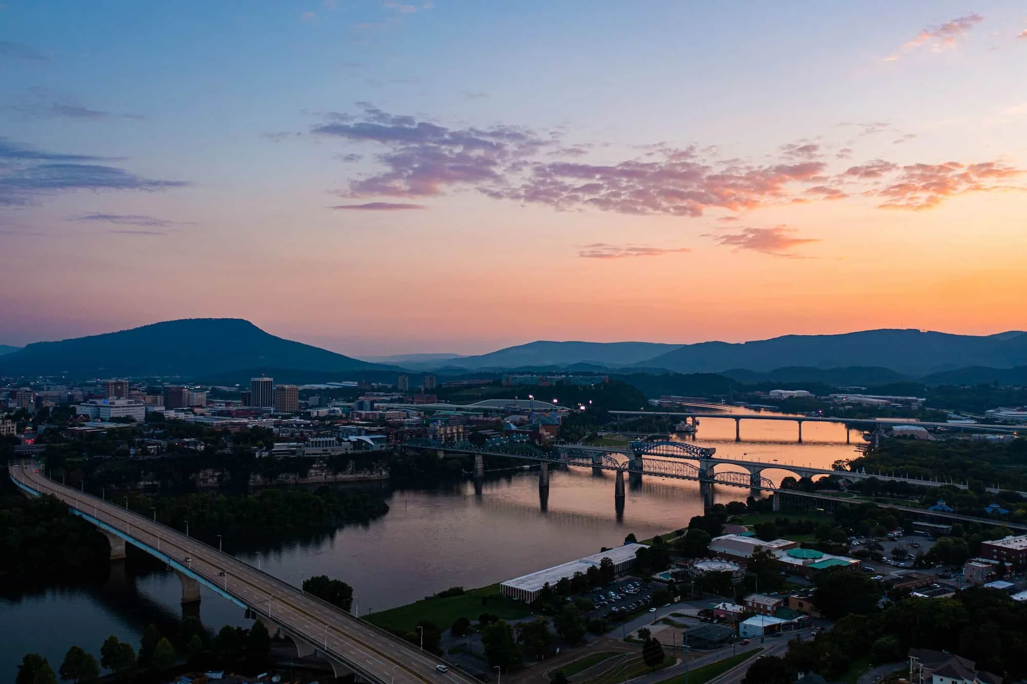 Aerial sunset view of Chattanooga, Tennessee featuring the Tennessee River, downtown skyline, and multiple bridges