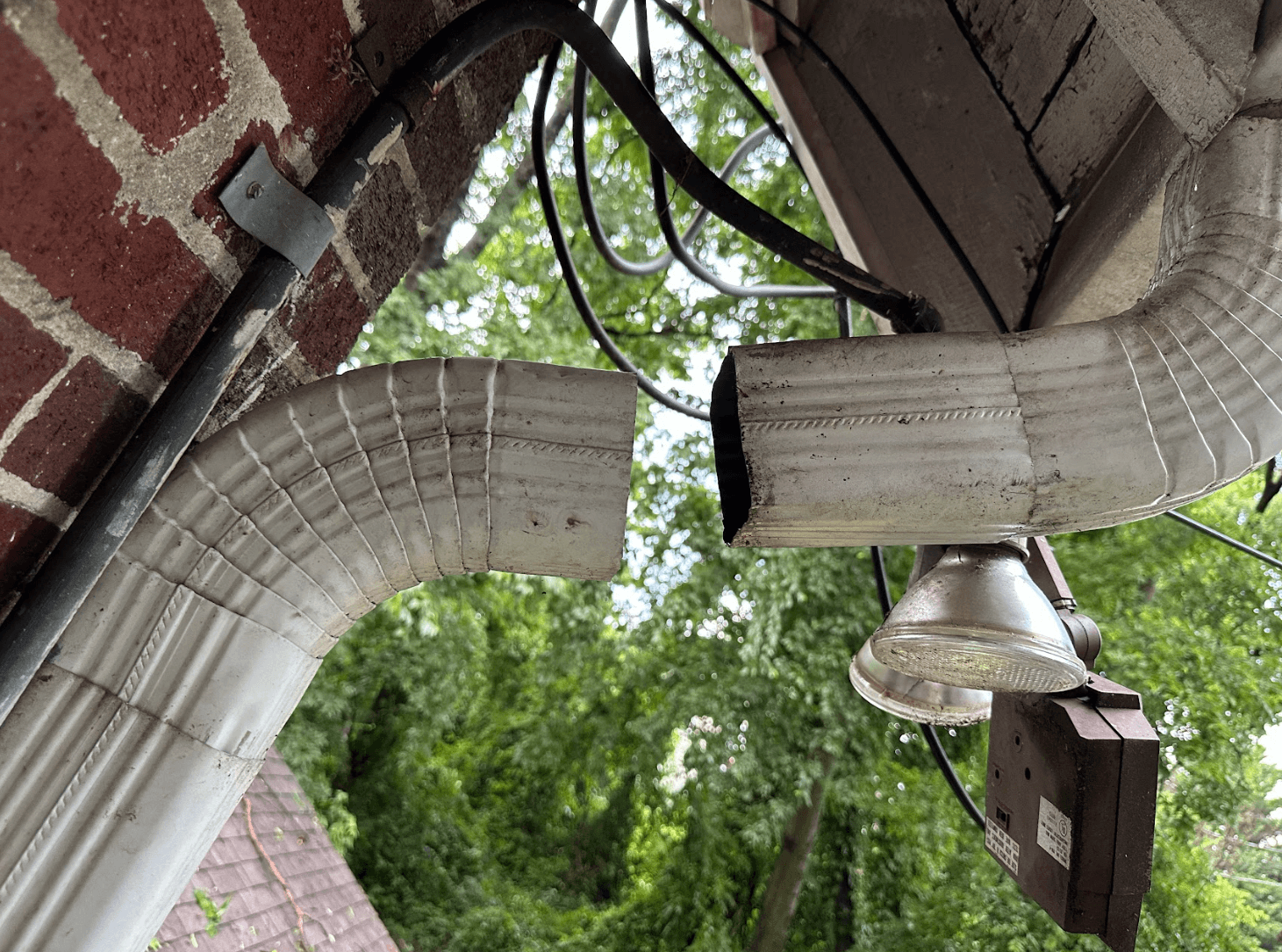 Damaged gutter and downspout disconnected at the joint, showing a break in the drainage system near a home in Chattanooga, Tennessee