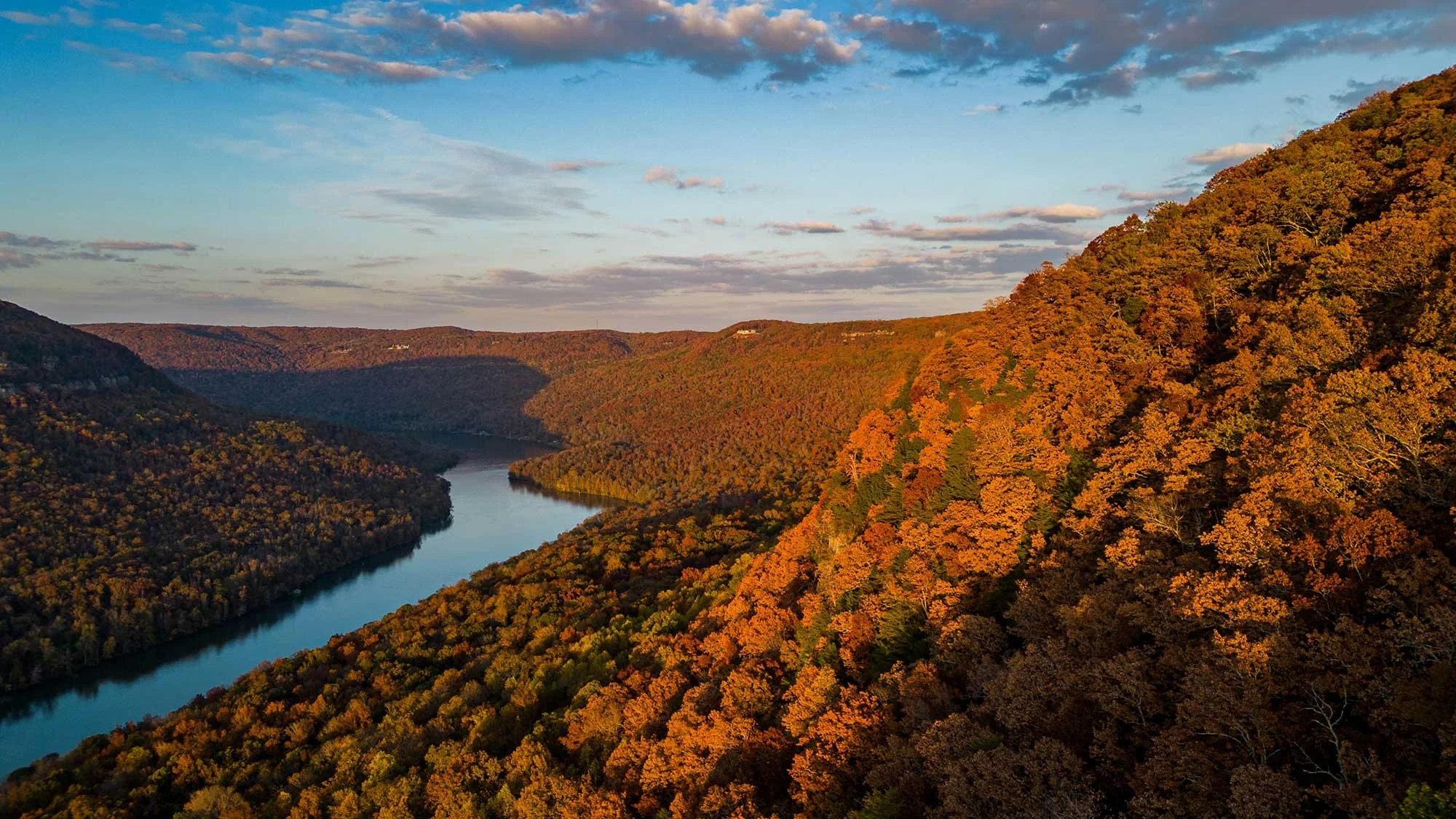Aerial view of the Tennessee Valley during autumn, showing the Tennessee River winding through densely forested mountains with vibrant fall foliage.