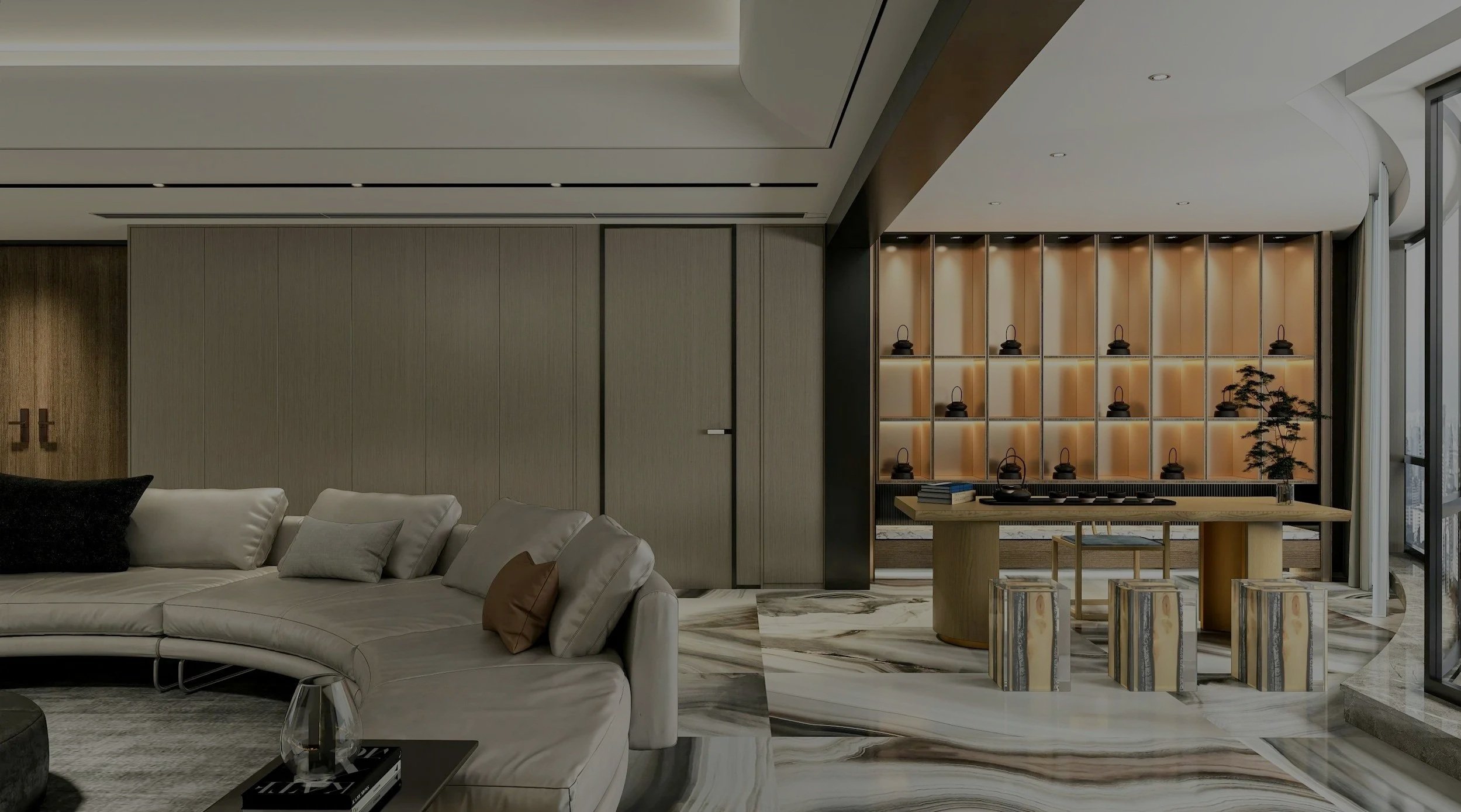 Modern living room with a large beige sectional sofa, marble flooring, a wooden dining table with stools, and decorative shelves with teapots and a small tree near a floor-to-ceiling window.