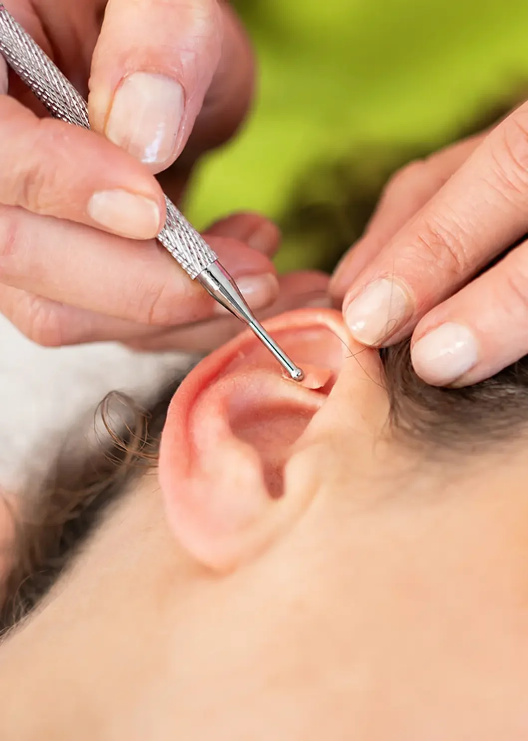 A person receiving an ear cleaning with a medical tool, during a checkup or treatment.
