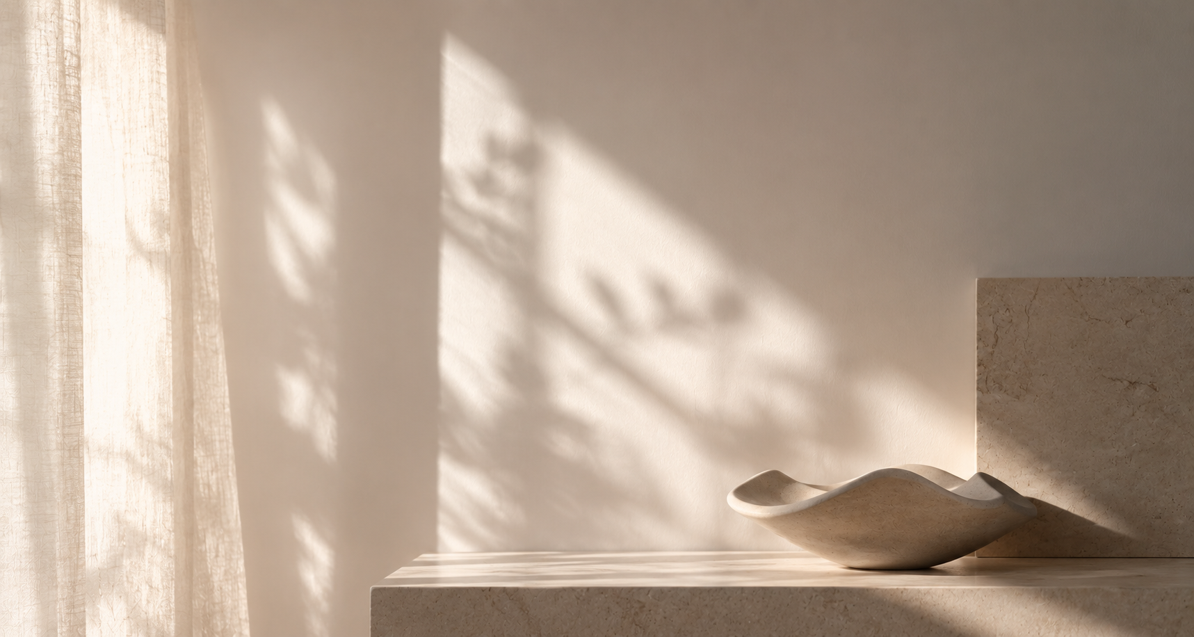 Minimalist interior scene with soft natural light casting gentle shadows across a neutral wall, featuring a sculptural ceramic bowl on a stone surface beside a sheer curtain.