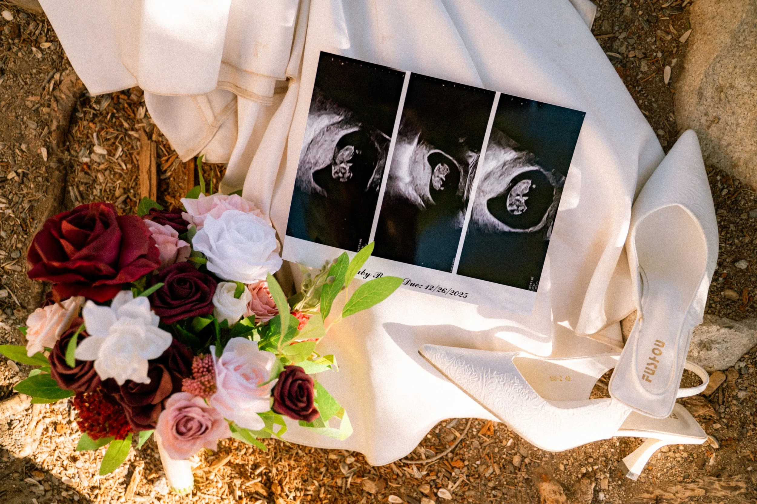 Ultrasound images of a fetus, a bouquet of red, pink, and white roses, and a white cloth on the ground.