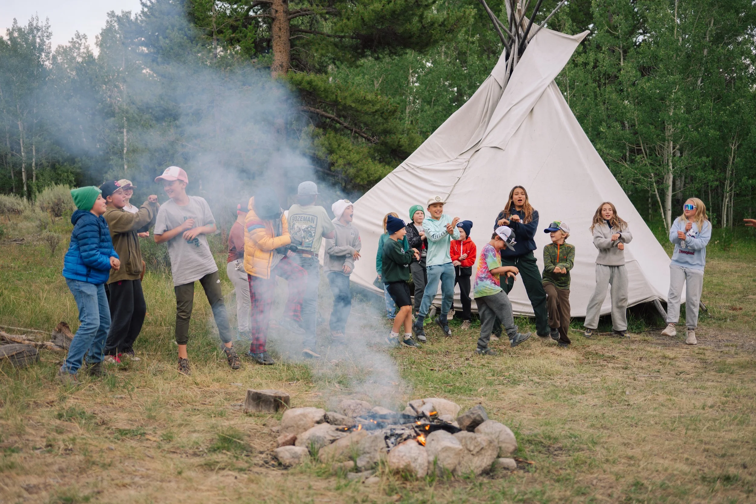 Group of campers dancing around a campfire at Camp New Fork.