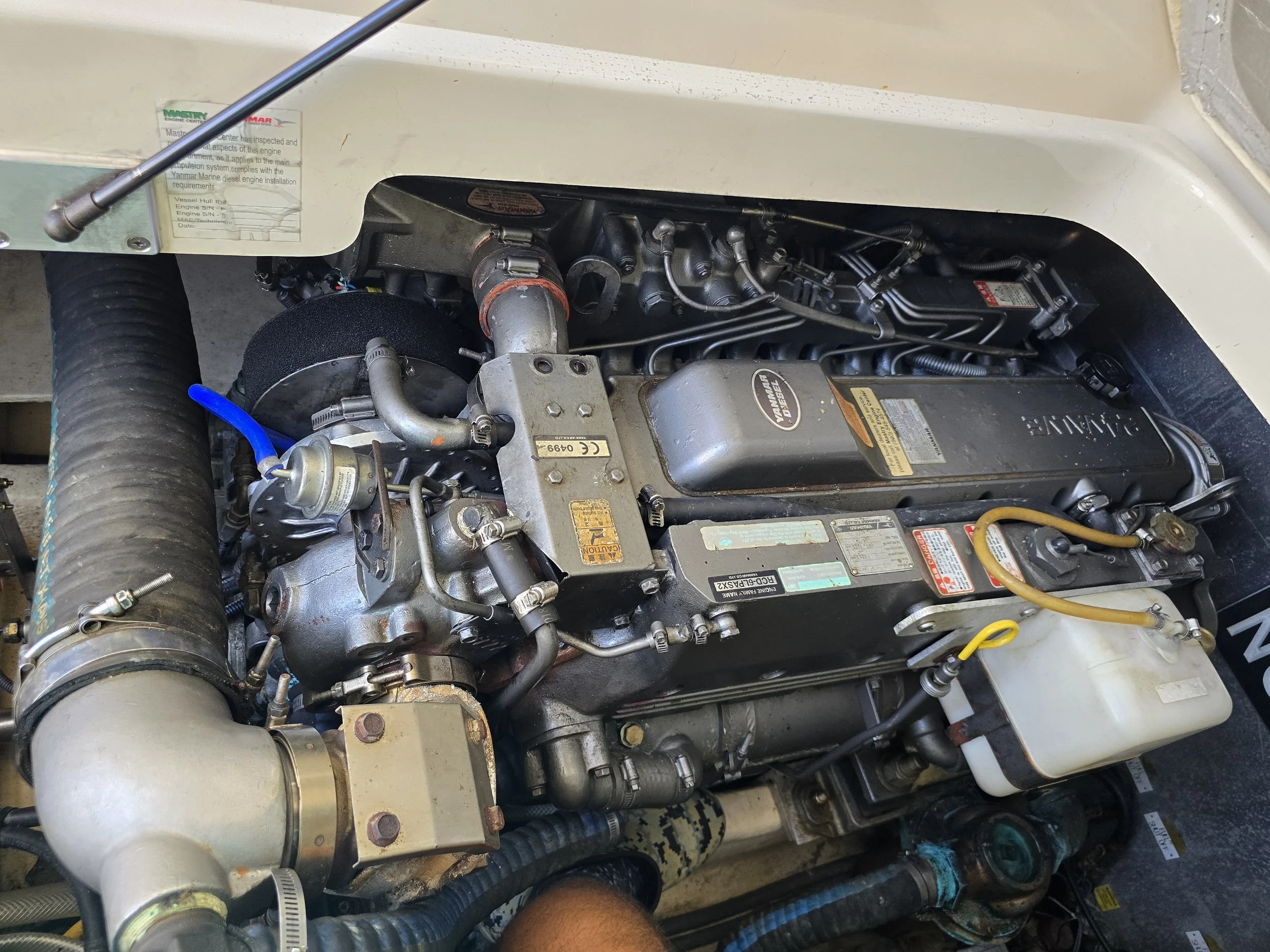 Marine diesel engine with various pipes, wiring, and components in a boat engine compartment.