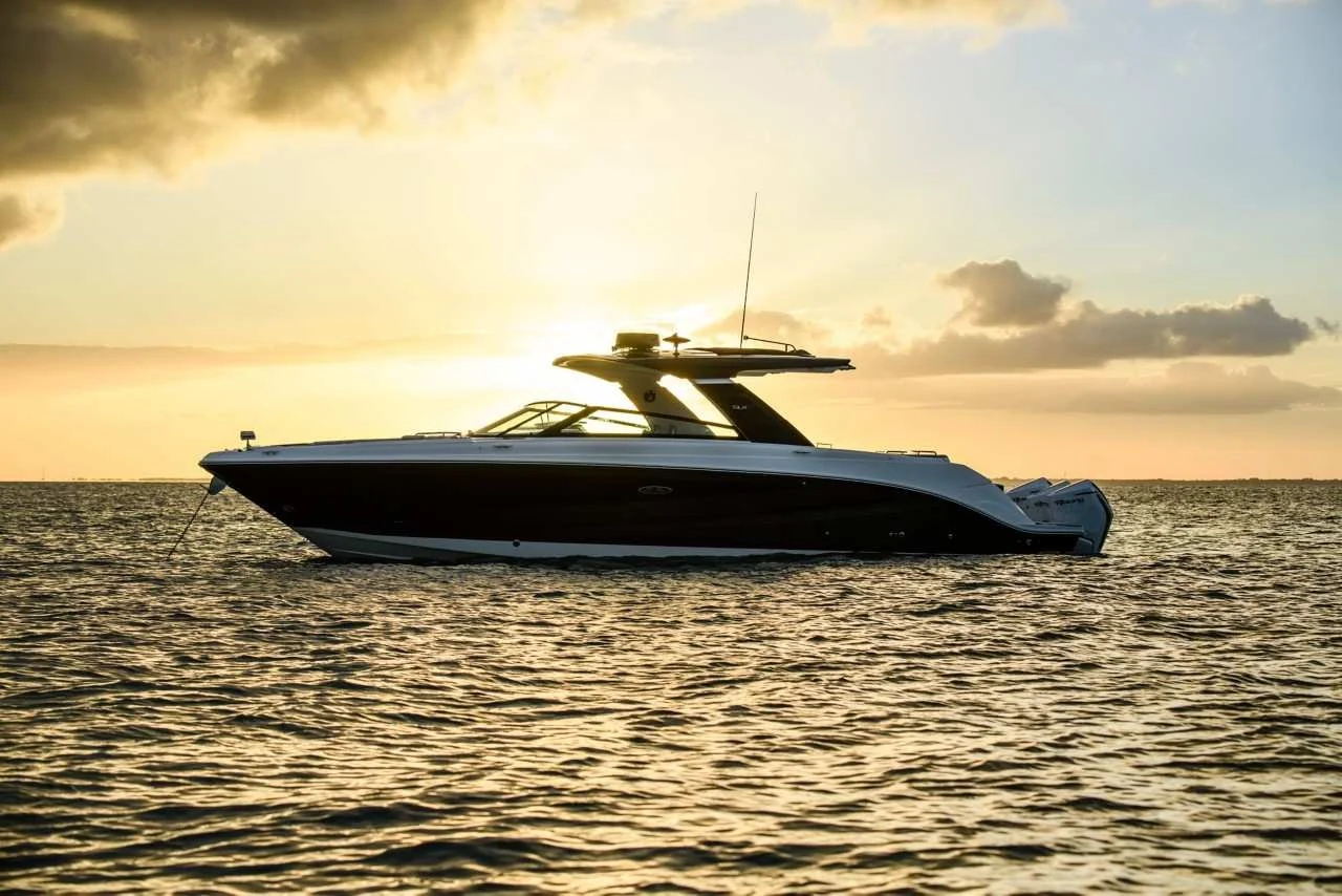 A yacht floating on the ocean during sunset.