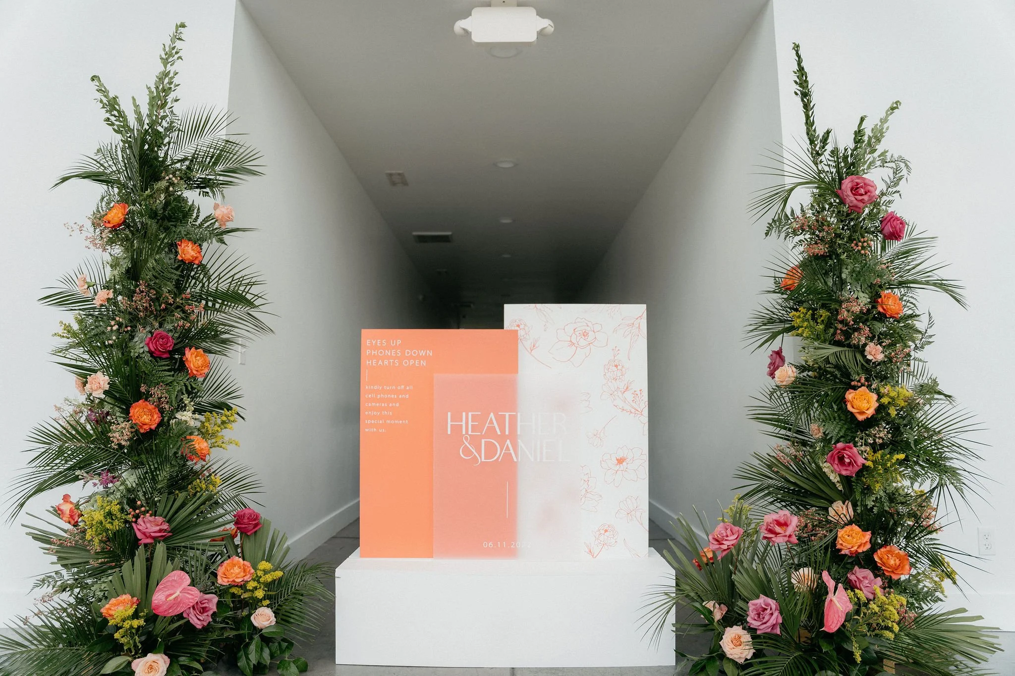 Welcome sign by Reverie Decor, flanked with large tropical floral pillars