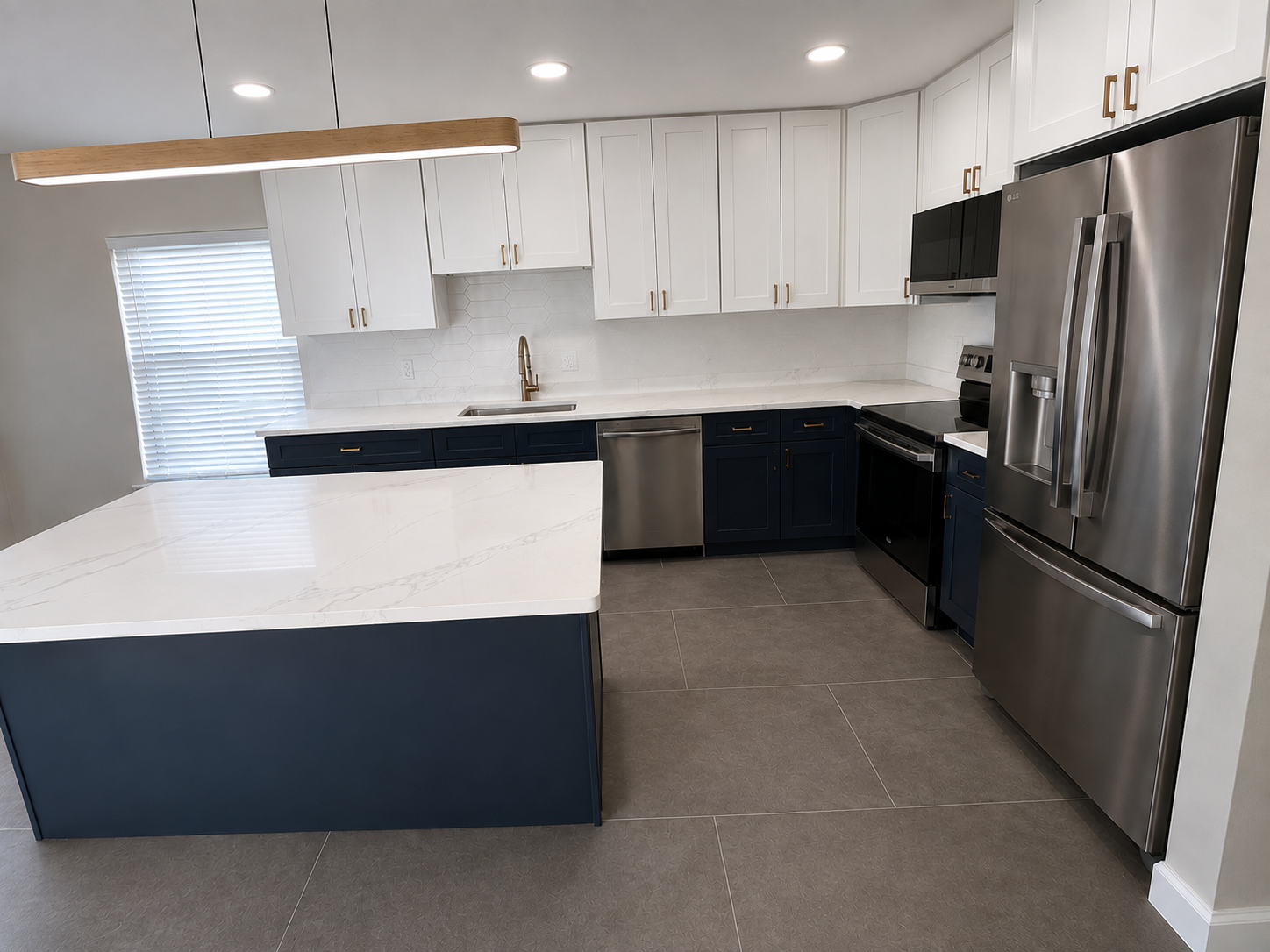 Modern kitchen with new stainless steel appliances, quartz countertops, and large cabinets. 