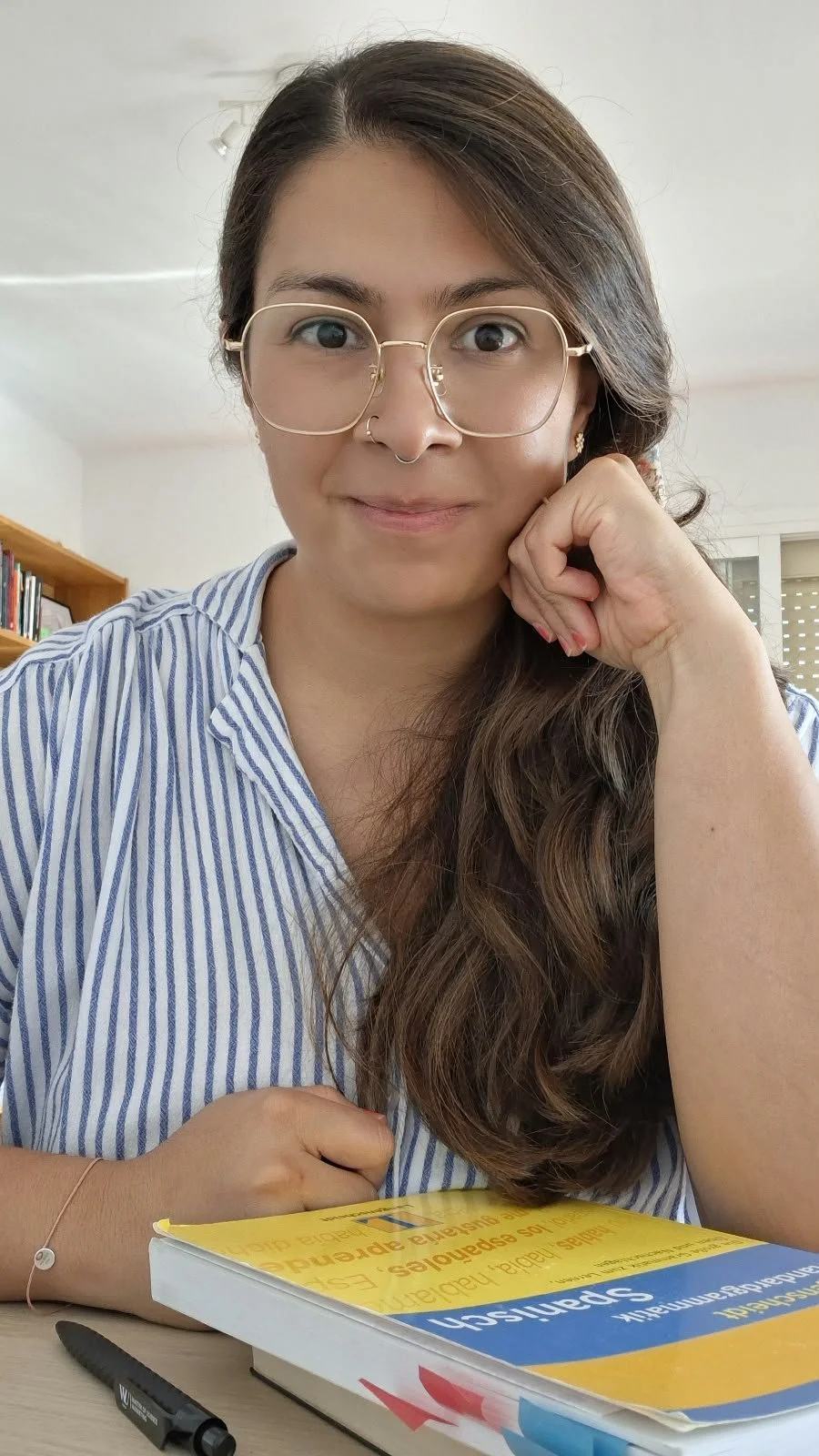 Retrato de Gloria, profesora de Español online. Mujer con gafas y pelo castaño, mira  la la cámara sonriente .