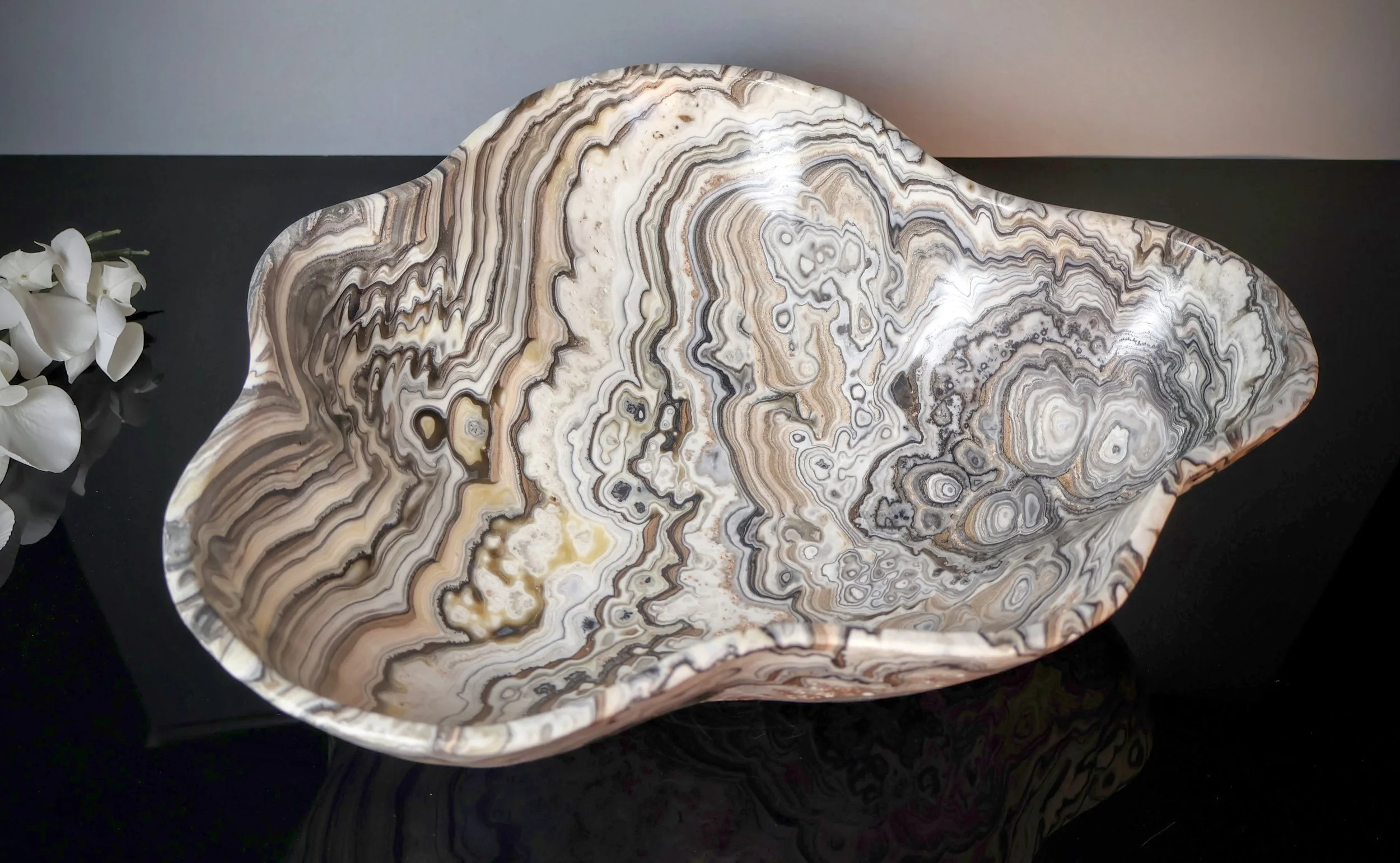 Banded black and white layers of an onyx bowl, photographed close-up on a black surface.
