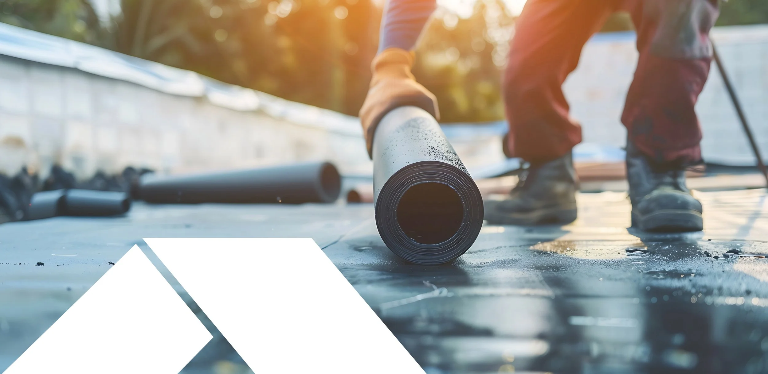 Construction worker installing rolled roofing membrane on a rooftop in sunlight