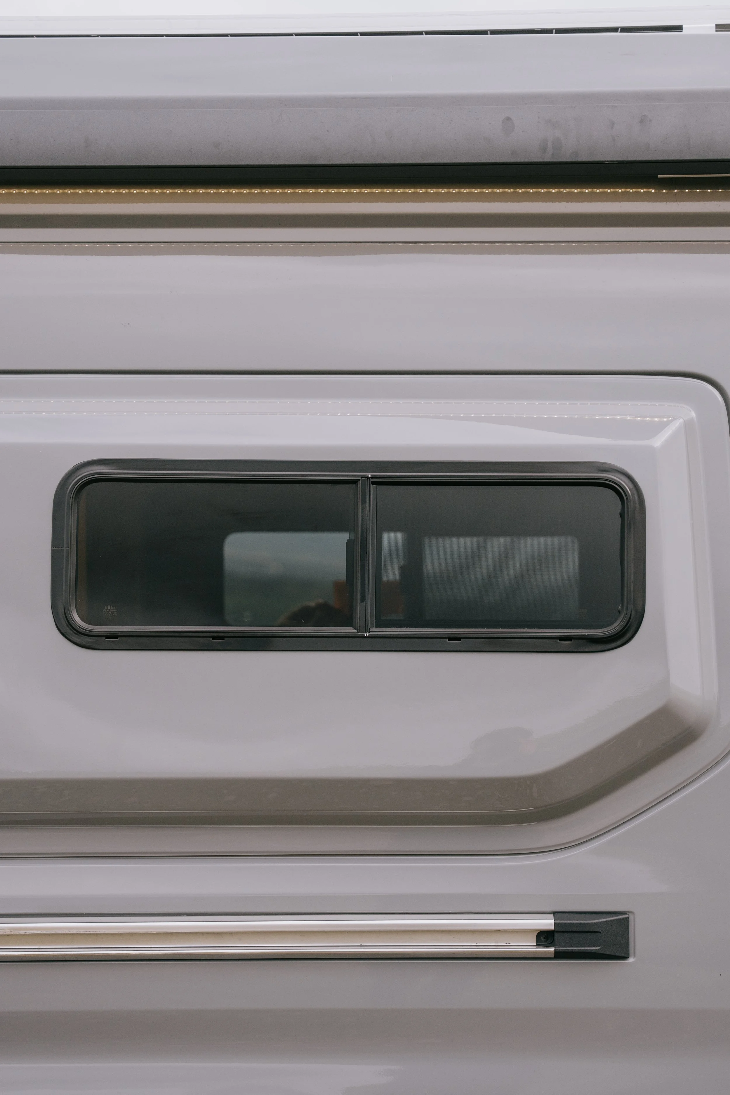 Close-up of a roadside emergency vehicle window, with a reflective surface and framed by a white body and black trim.