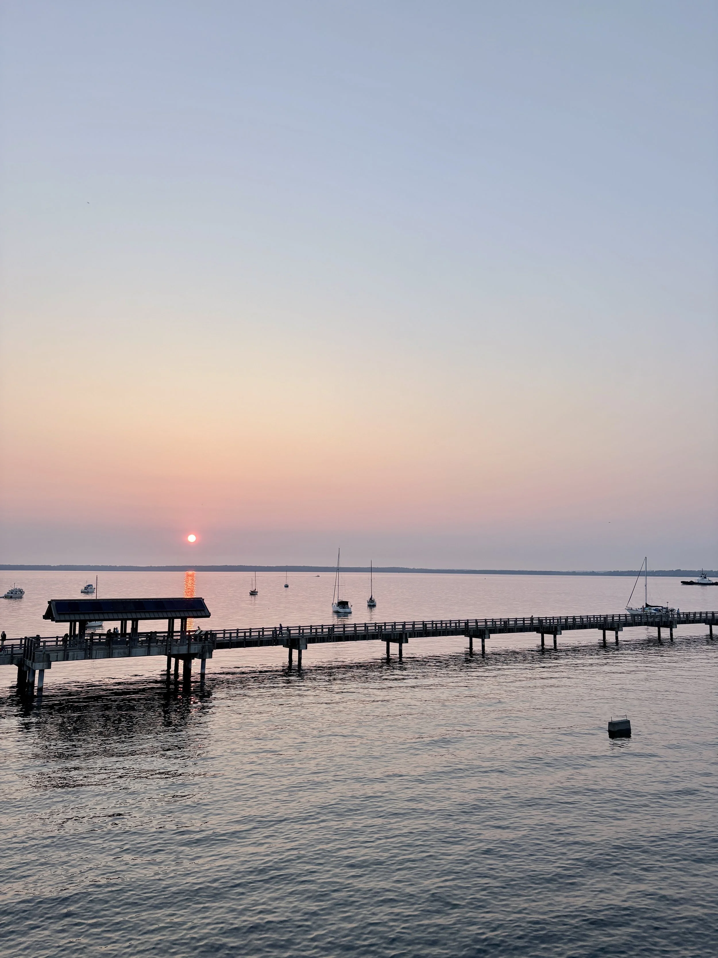 Sunset over calm water with boats, illustrating the peaceful lifestyle you can create through home organizing in Chehalis, WA