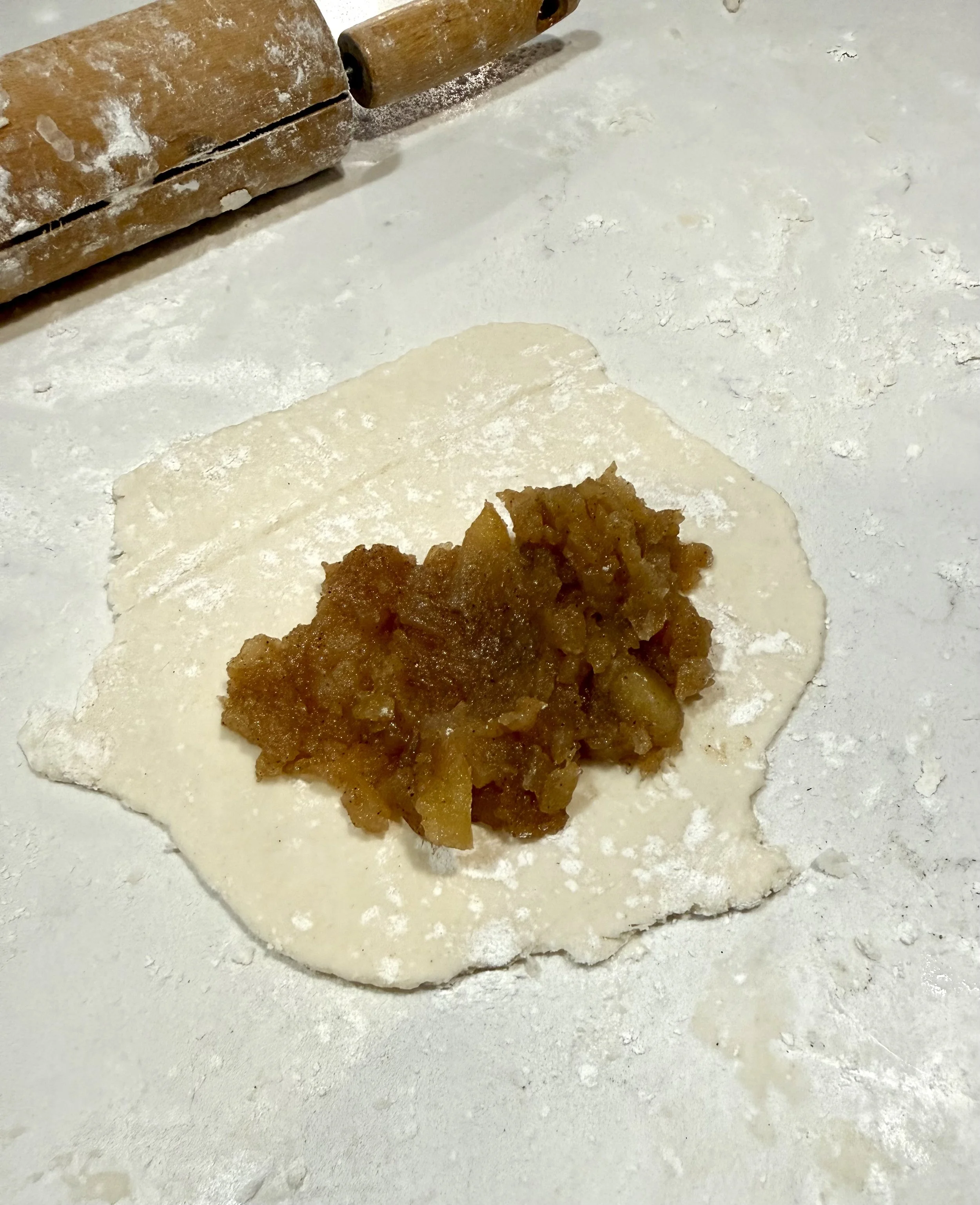 Fresh apple filling in the center of a round pastry dough circle, ready to be folded into a fried apple pie.