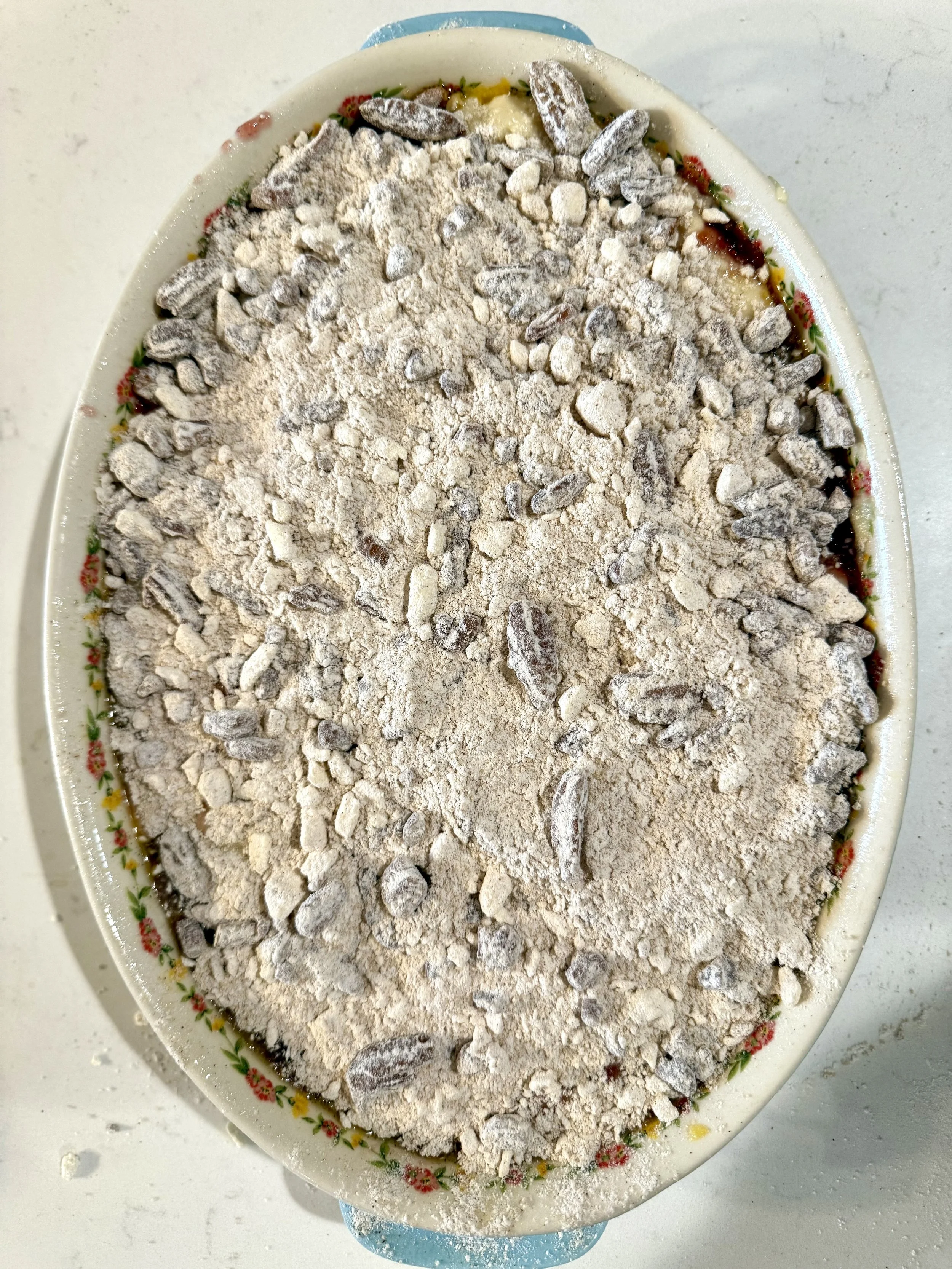 Unbaked cranberry orange coffee Cake topped with a thick pecan streusel layer in a round baking dish before going into the oven.