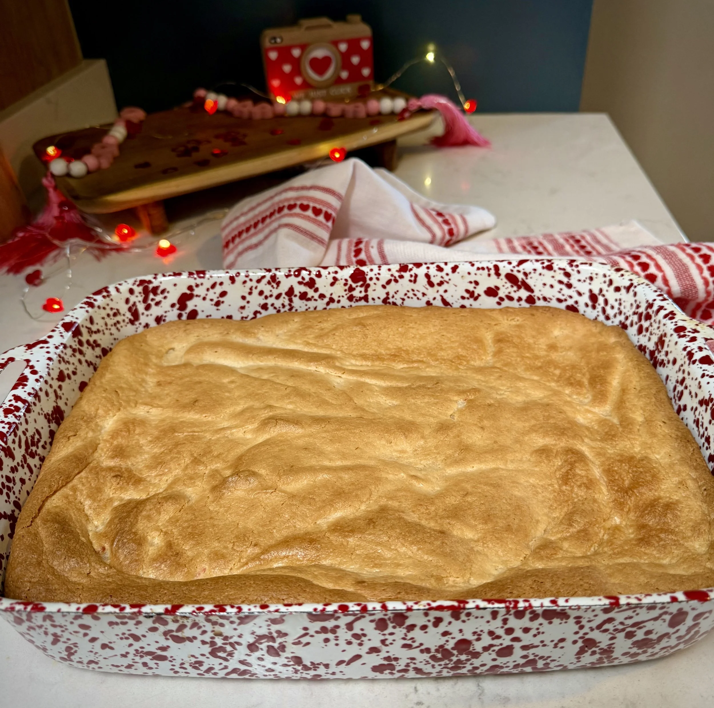 Red velvet gooey butter cake in a 9 X 13 speckled baking dish, ready to be cut into bars.
